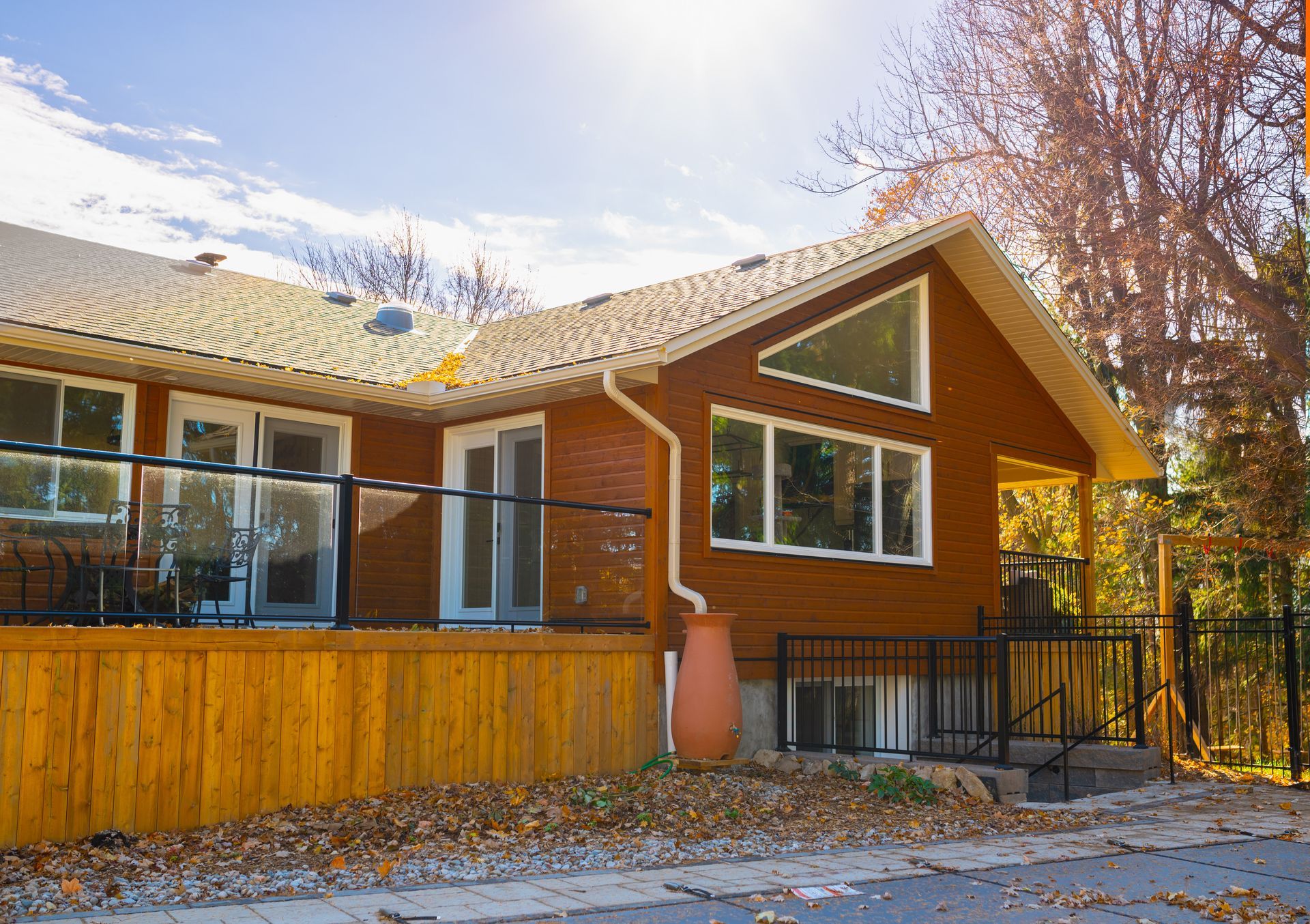 A brown house with a large deck and a wooden fence in front of it.