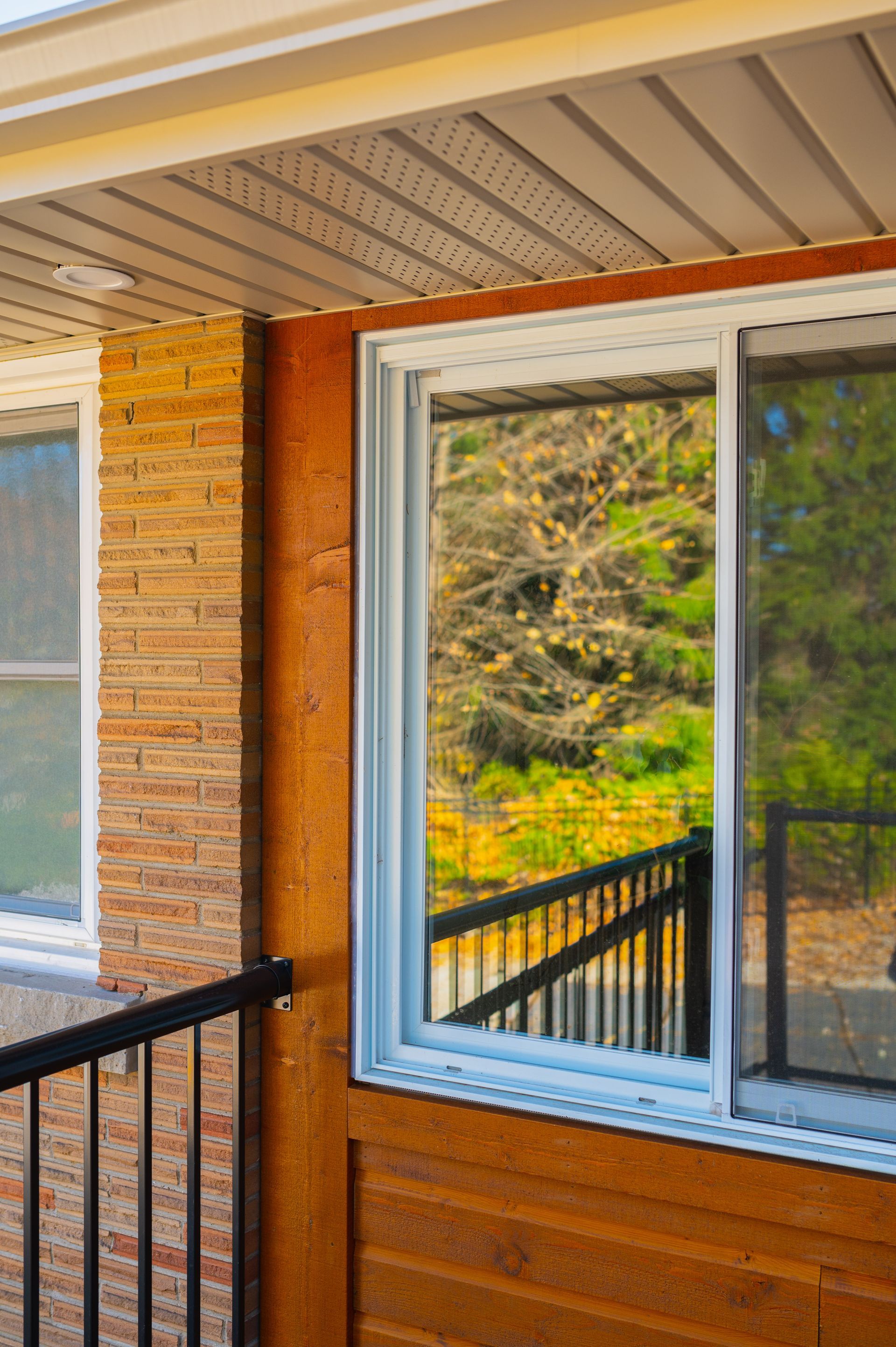 A brick house with a sliding glass door and a reflection of trees in the window.