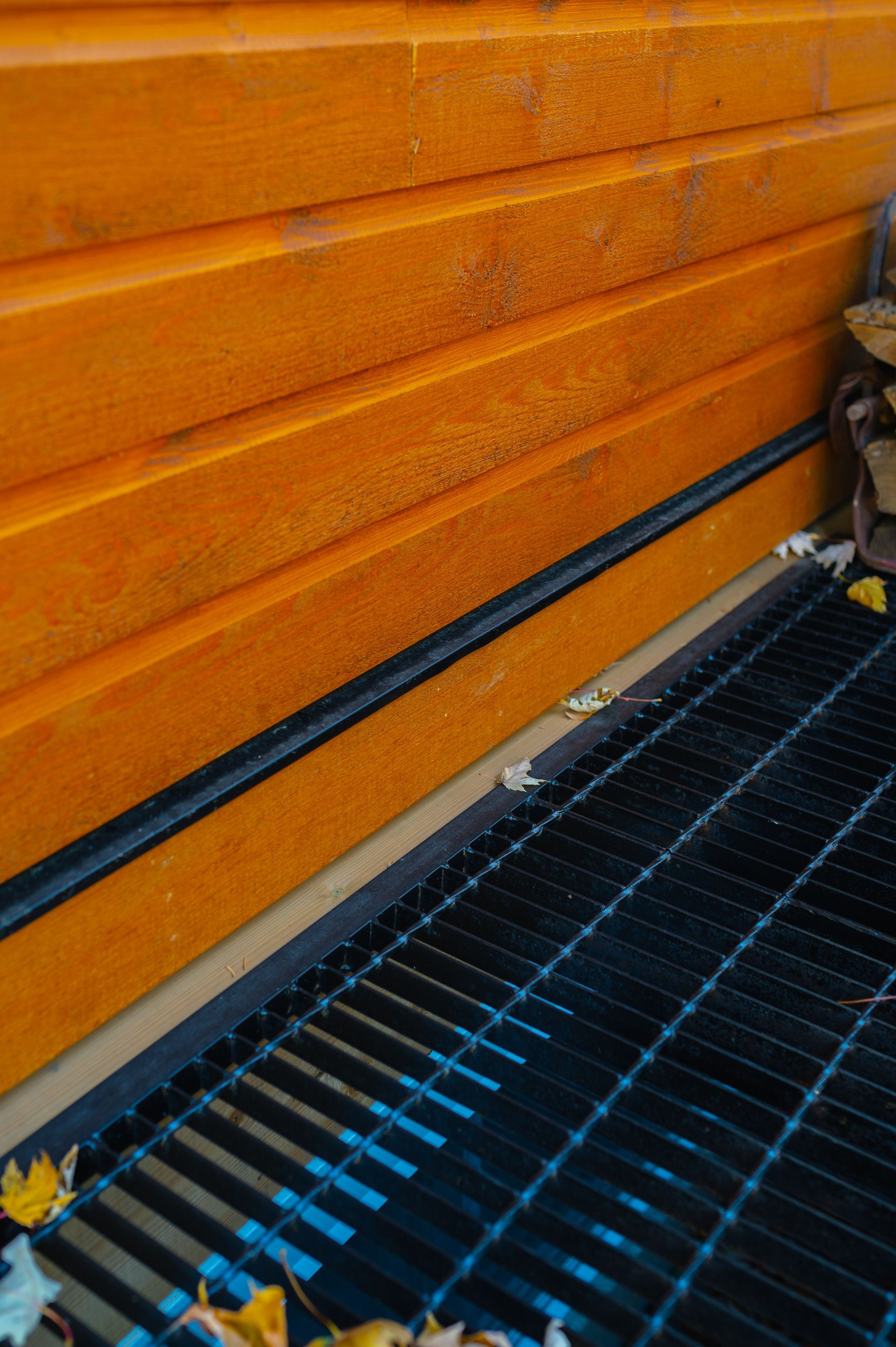 A close up of a metal grate next to a wooden wall.