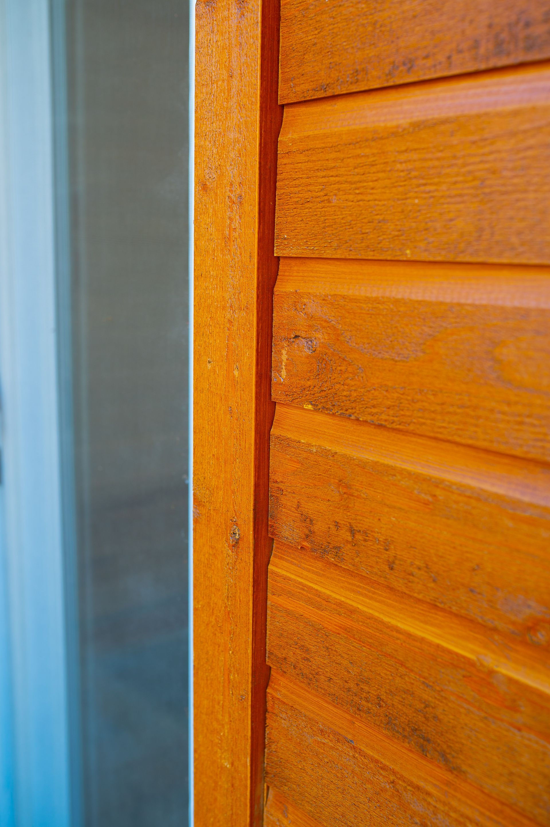 A close up of a wooden wall with a window in the background.
