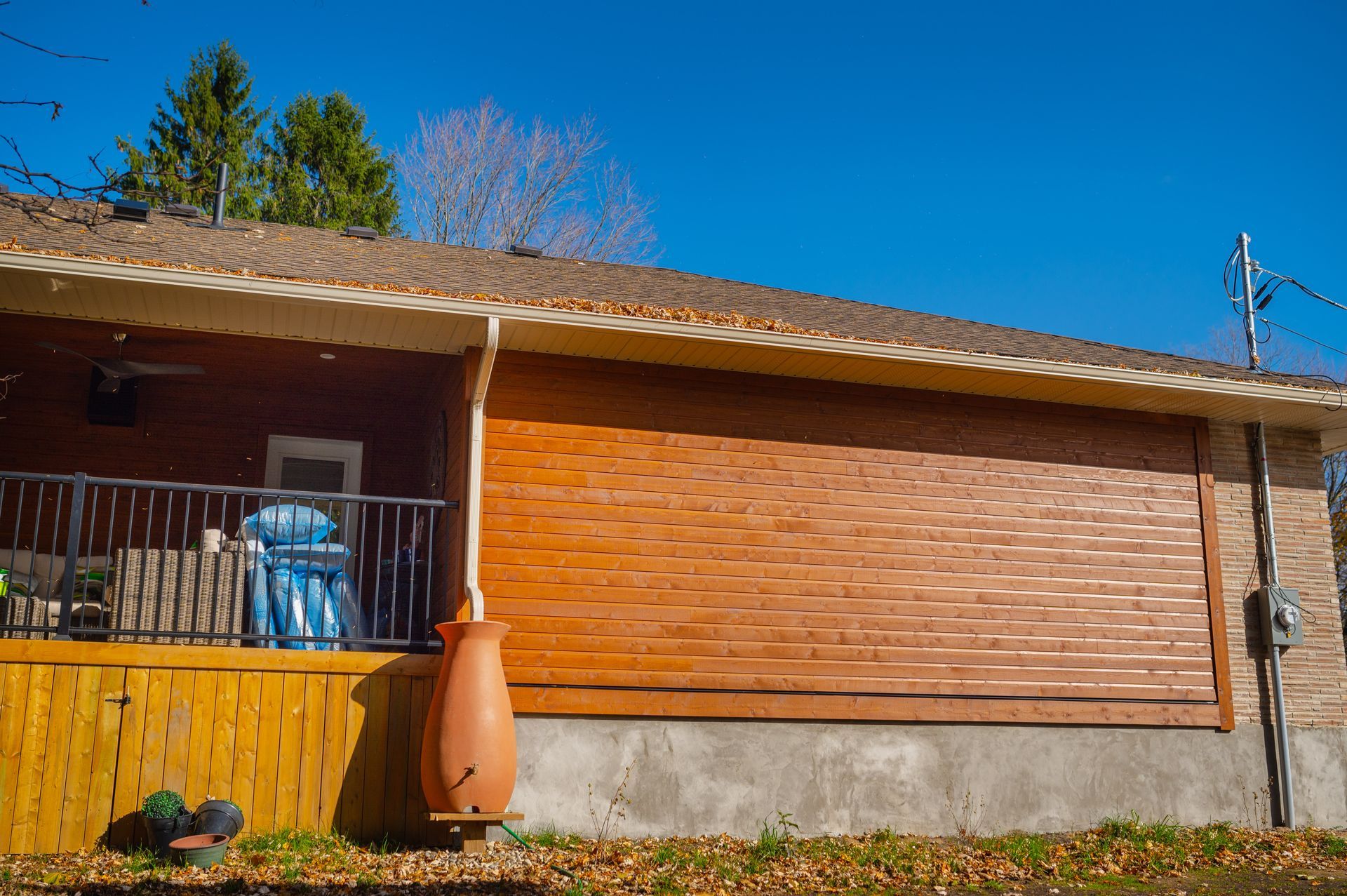 A house with a wooden porch and a water barrel in front of it.
