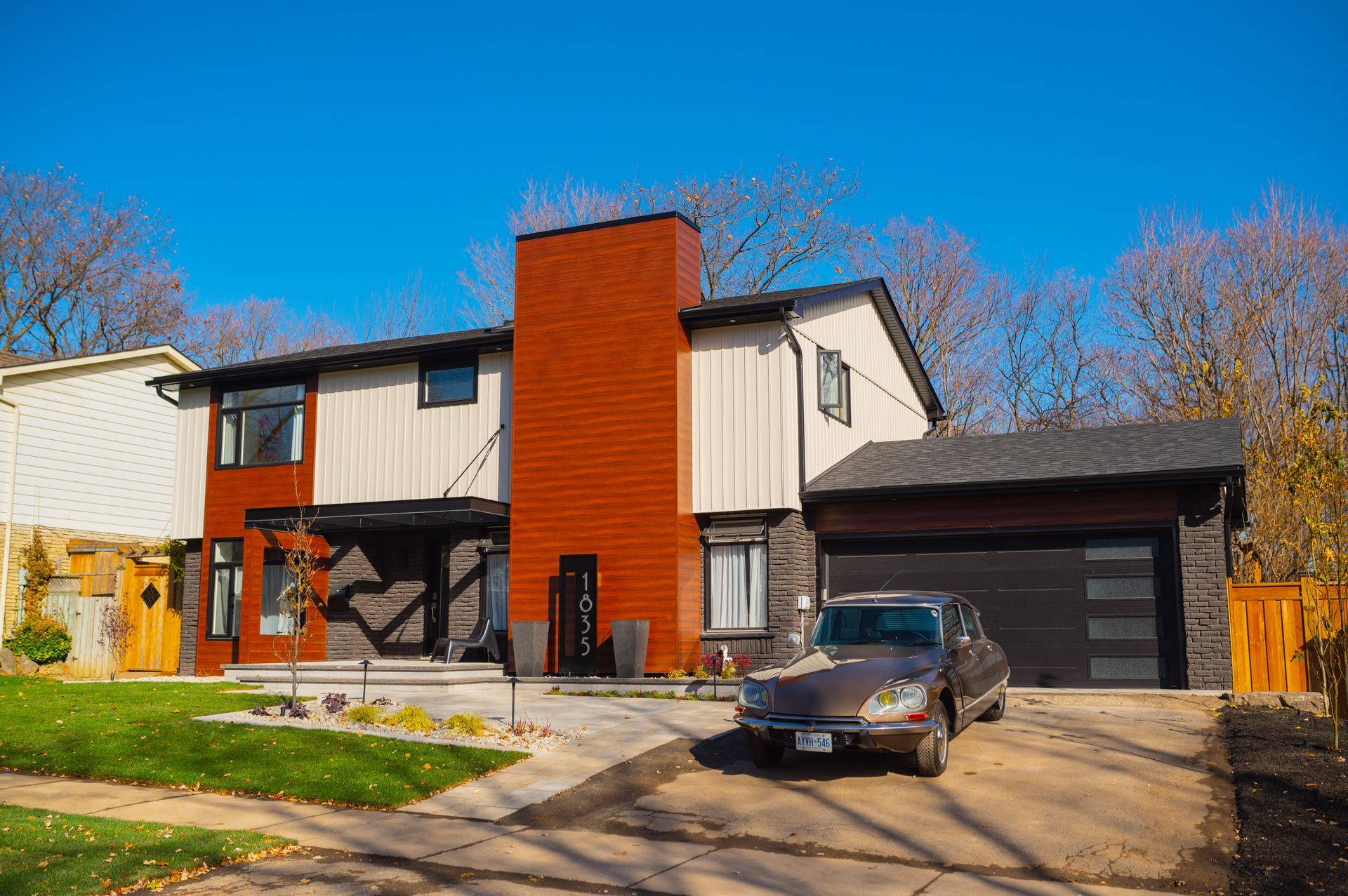 A car is parked in front of a large house.