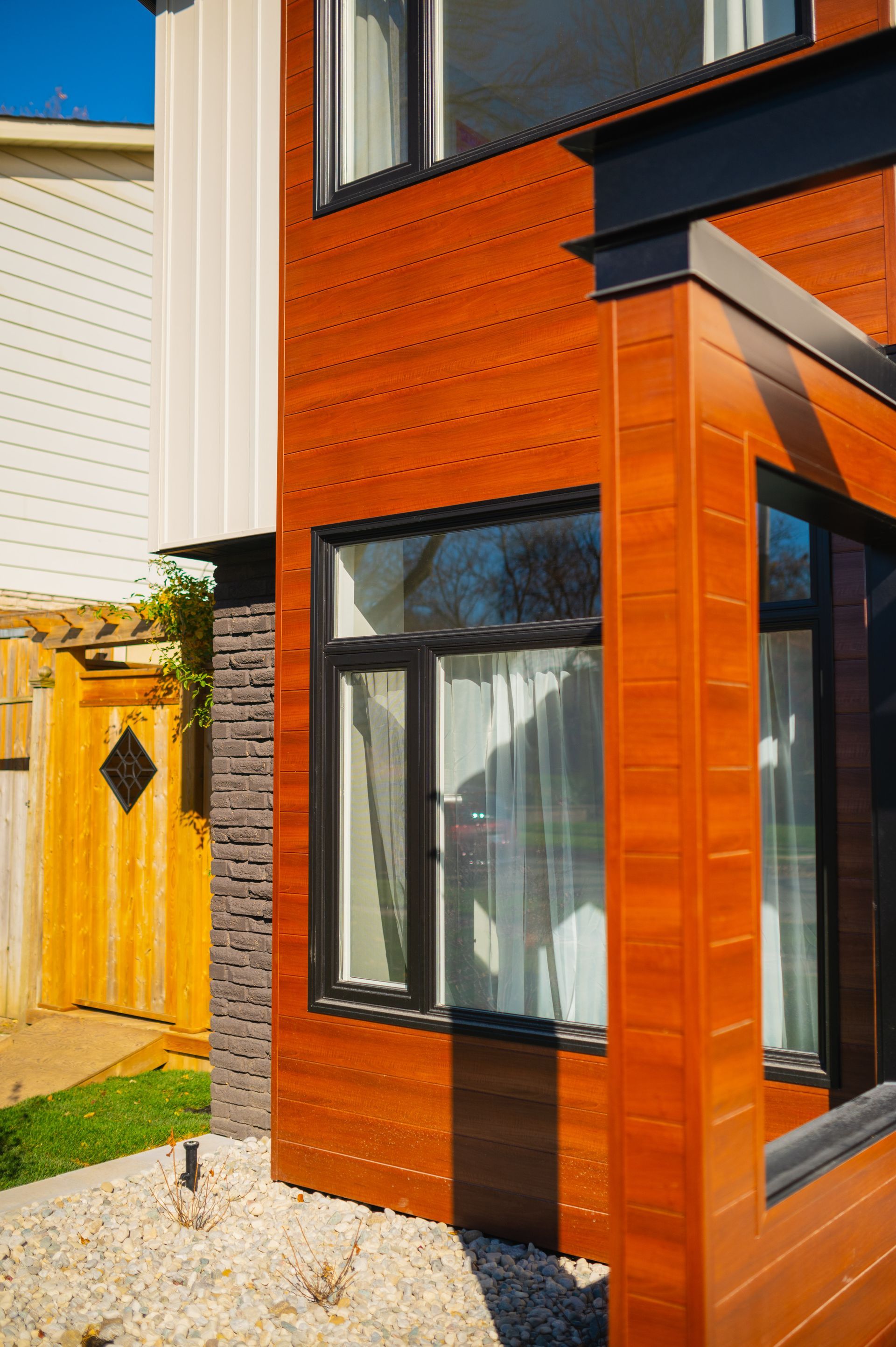 A close up of a house with a wooden facade and a lot of windows.