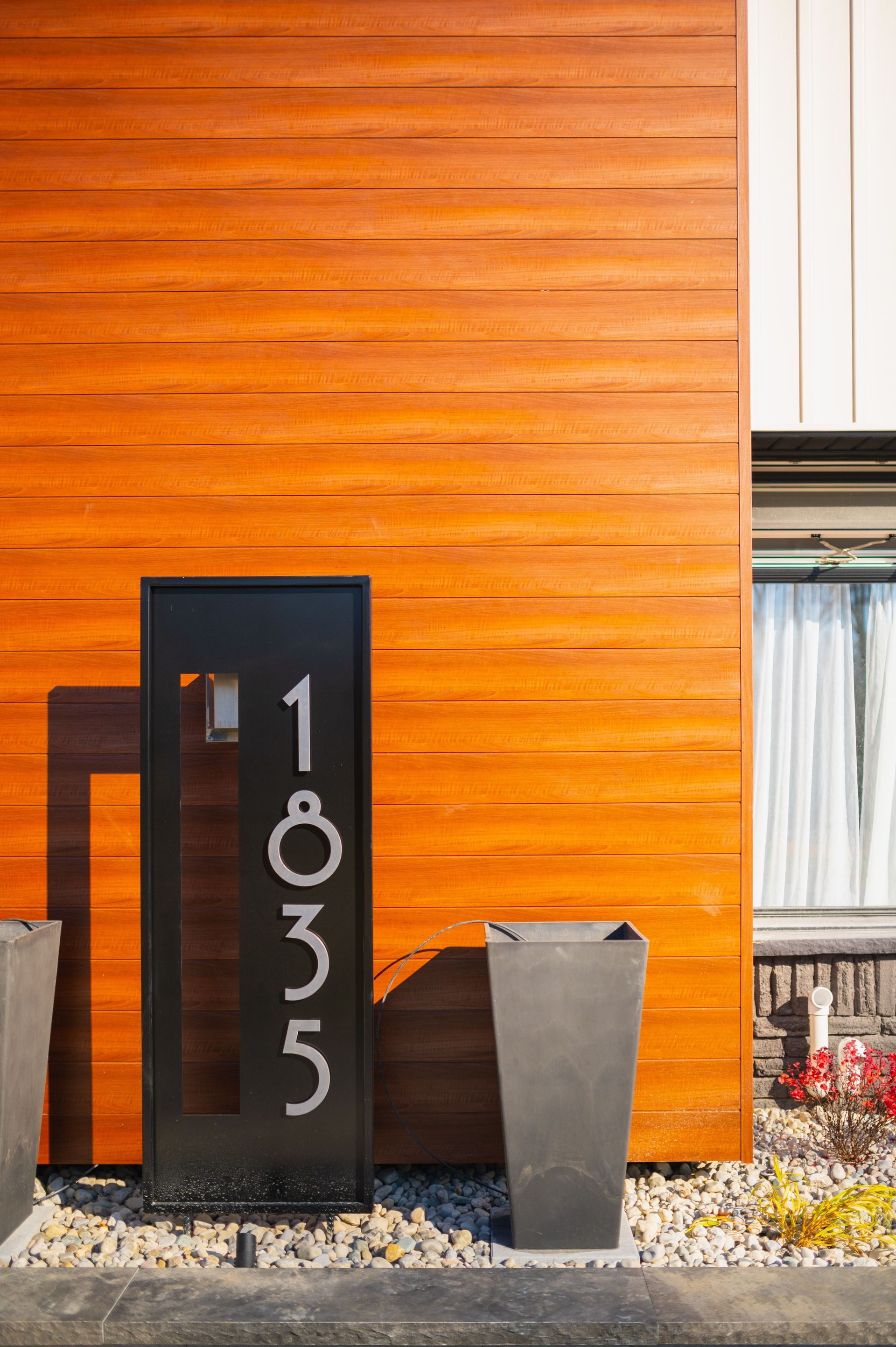 A house with a wooden siding and a black door with the number 1835 on it.