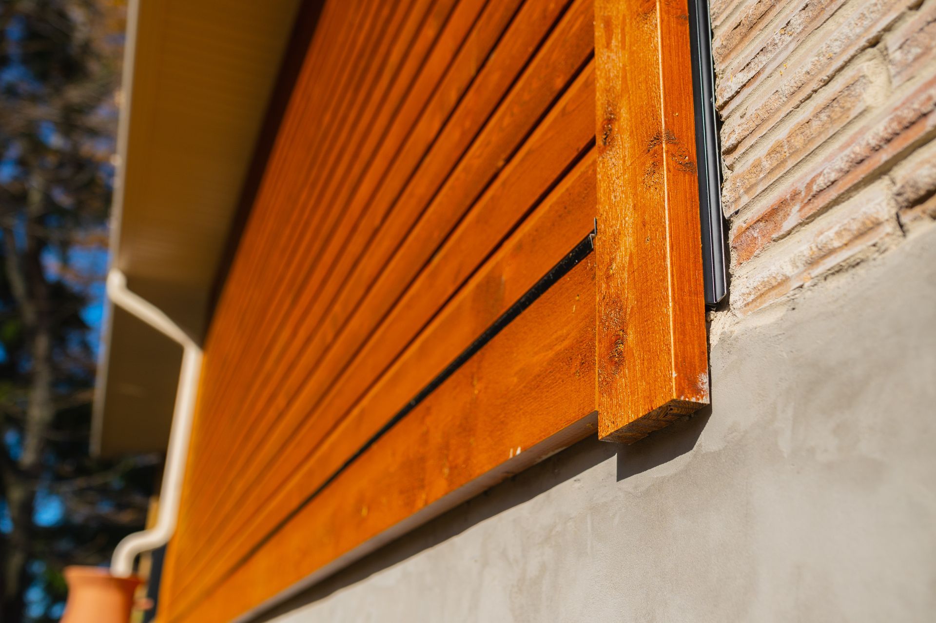 A close up of a wooden siding on a brick wall.