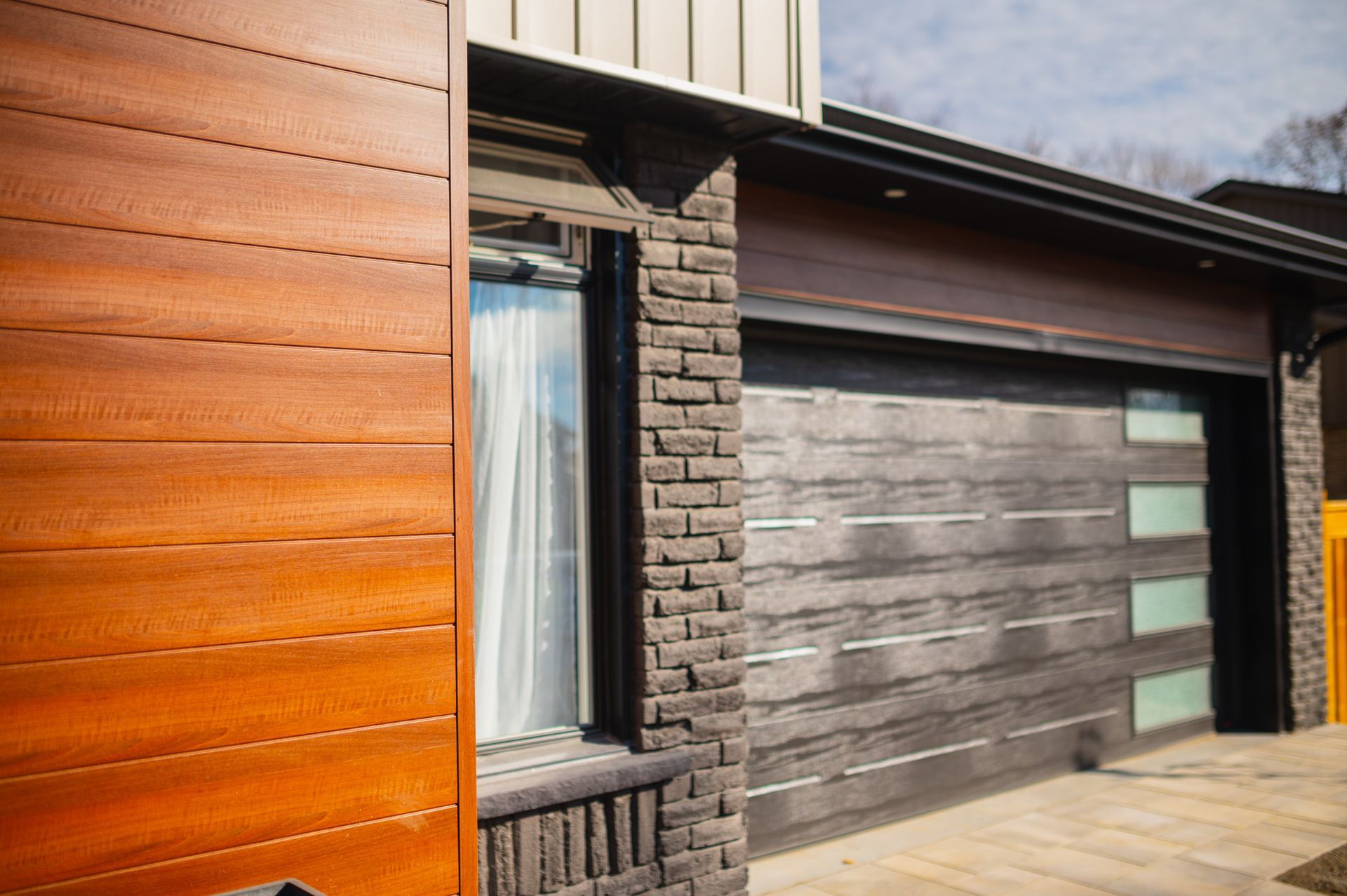 A house with a wooden garage door and a brick wall.