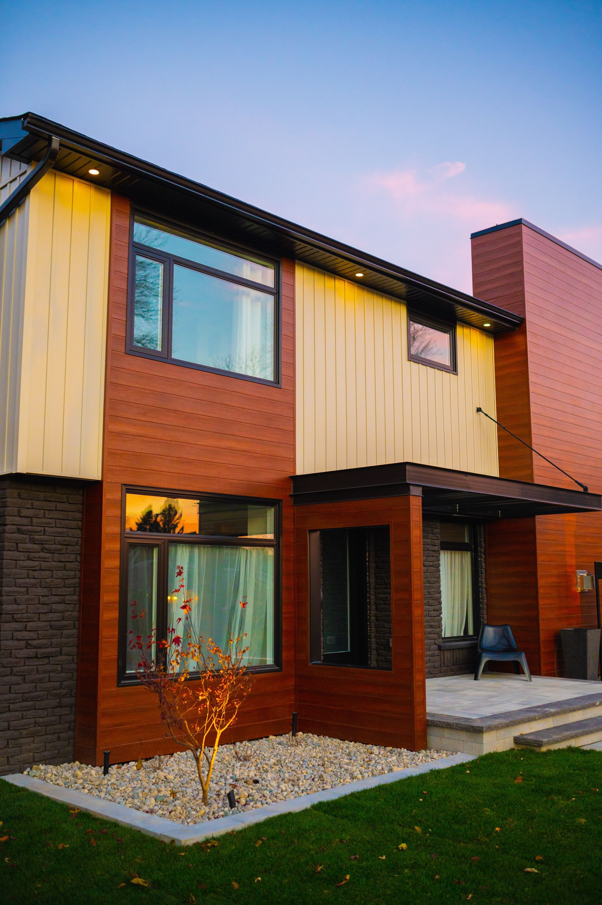 A large house with a lot of windows is sitting on top of a lush green lawn.