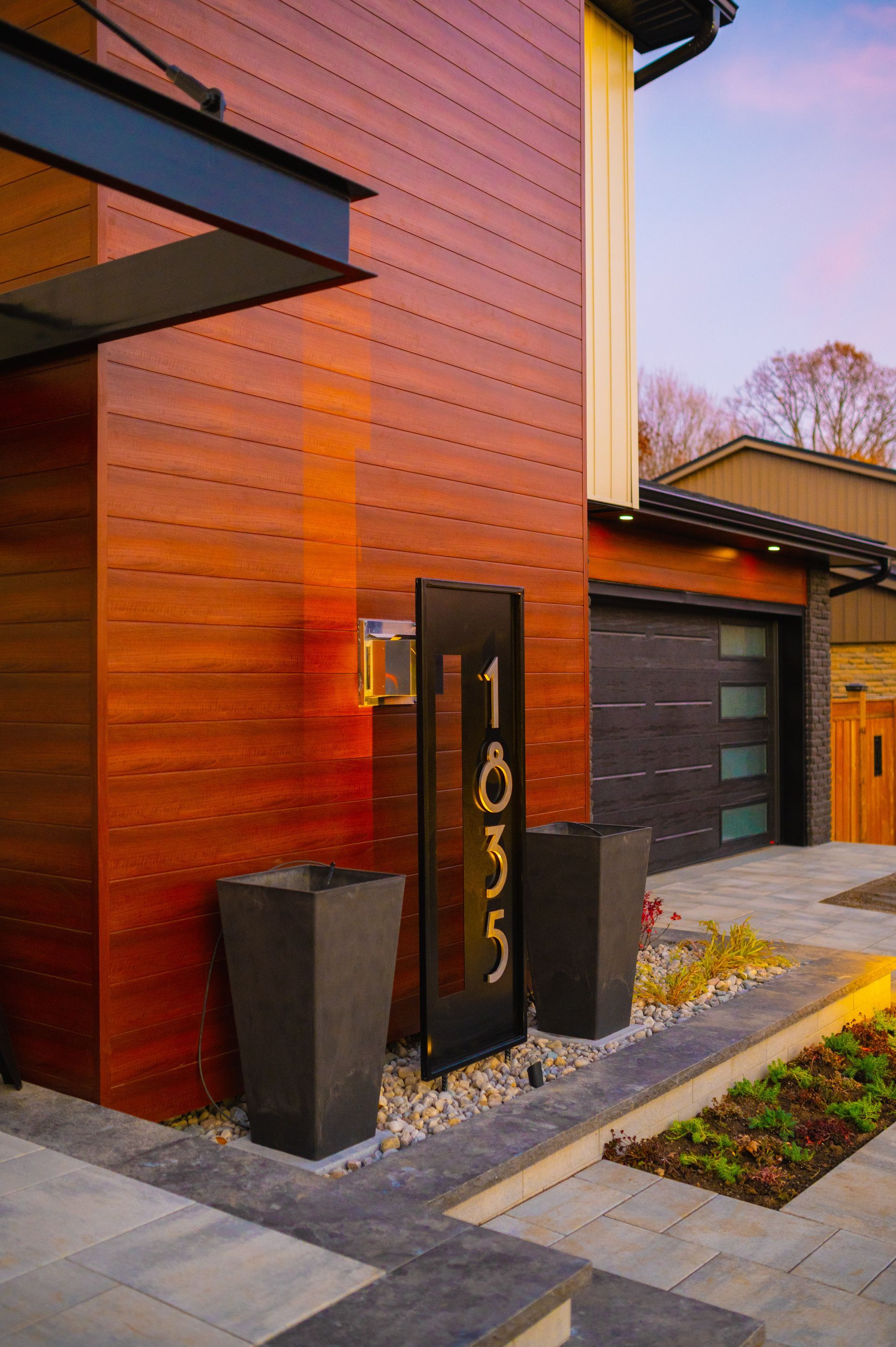 A modern house with a wooden facade and a black garage door.