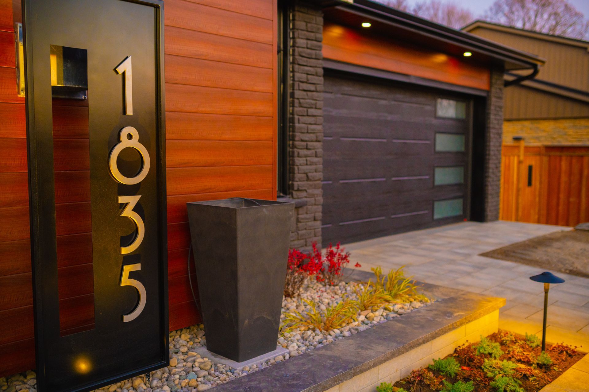 A house with a black garage door and a black mailbox in front of it.