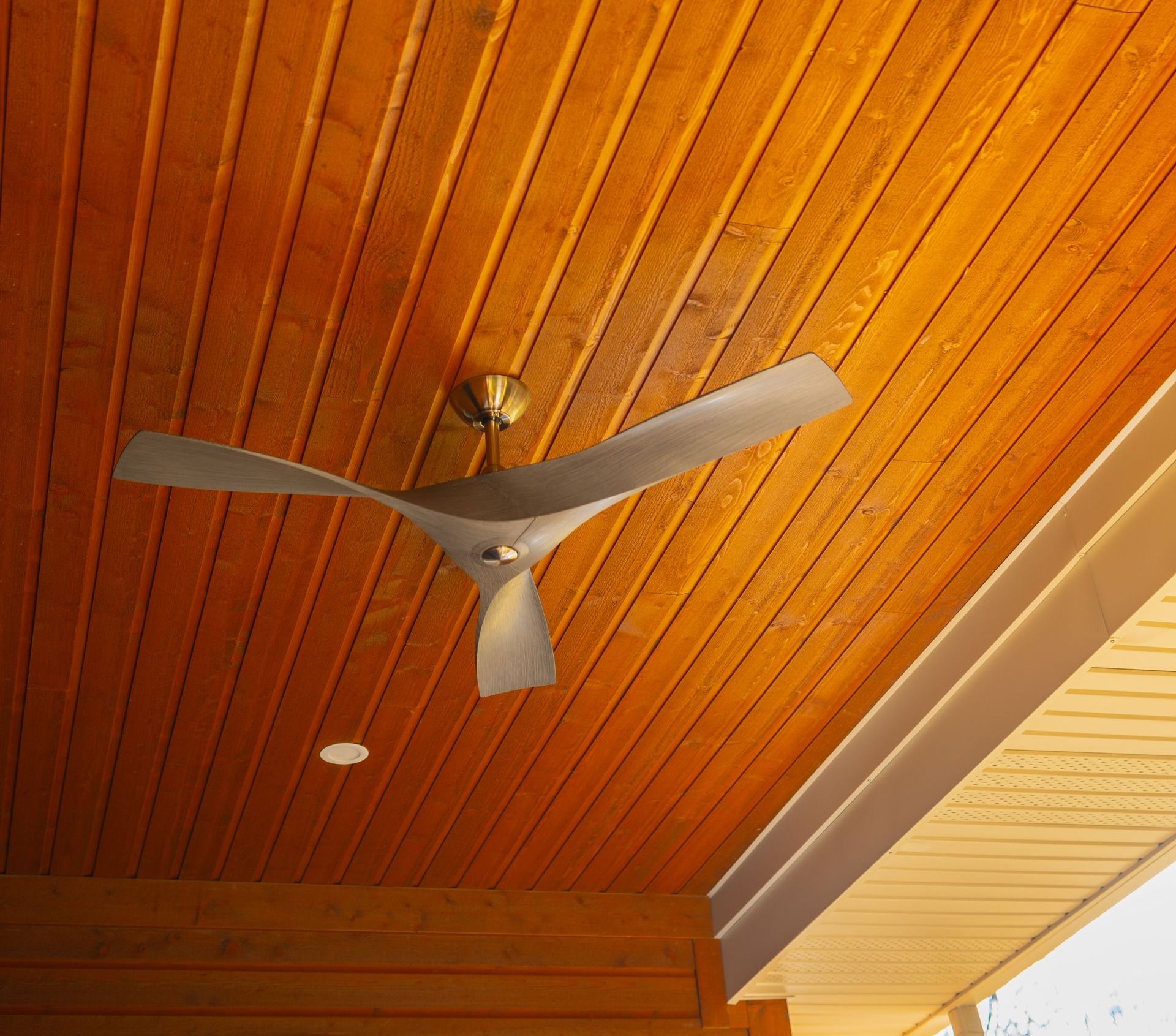 A ceiling fan is hanging from a wooden ceiling