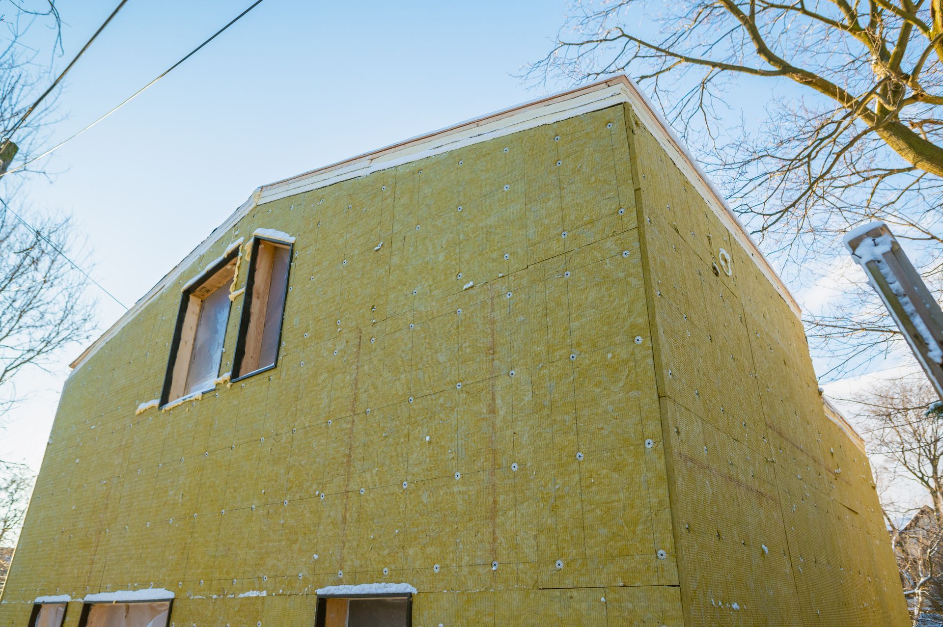 A yellow building with a tree in the background is being built.