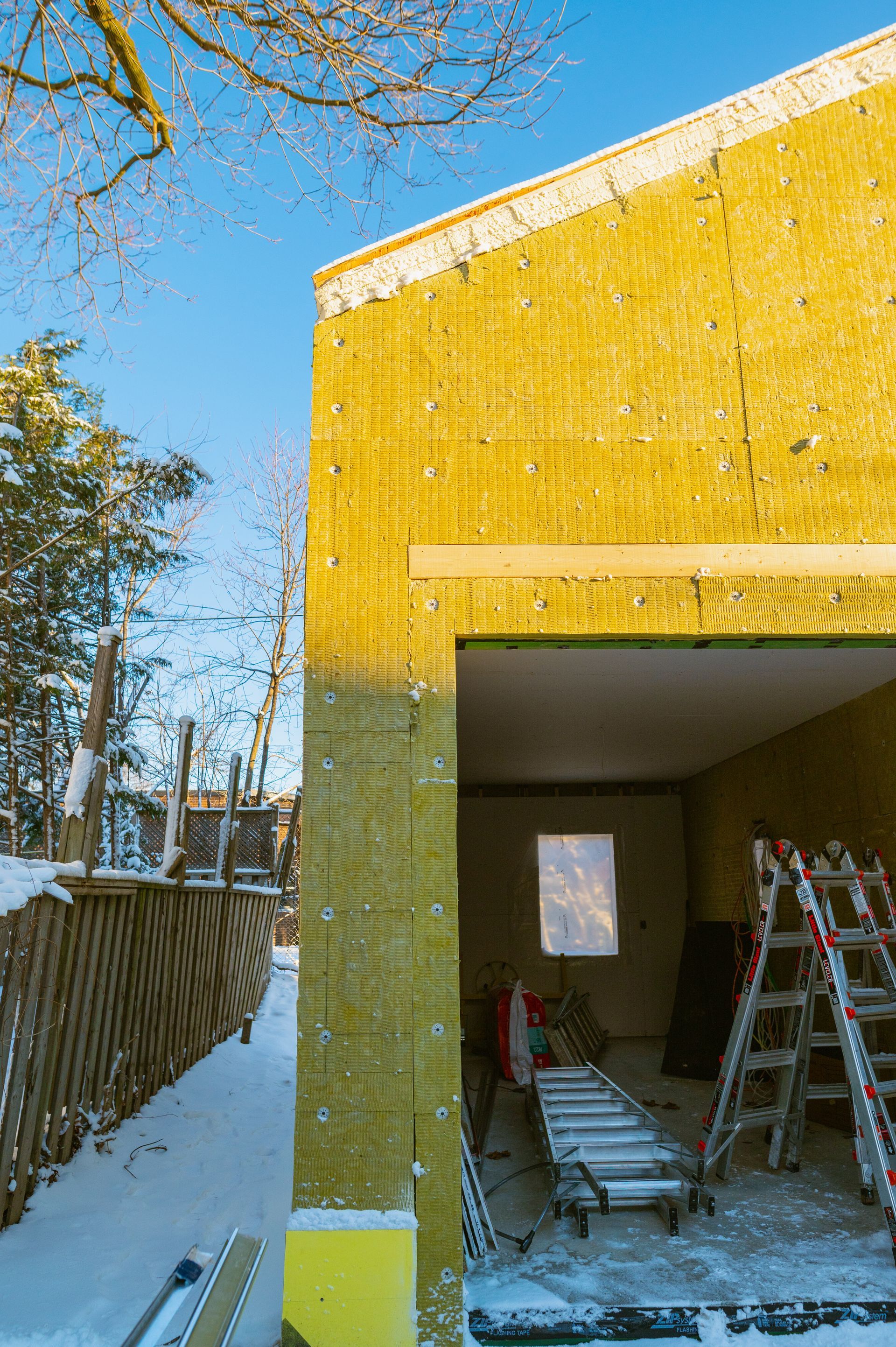 A yellow garage is being built in the snow.