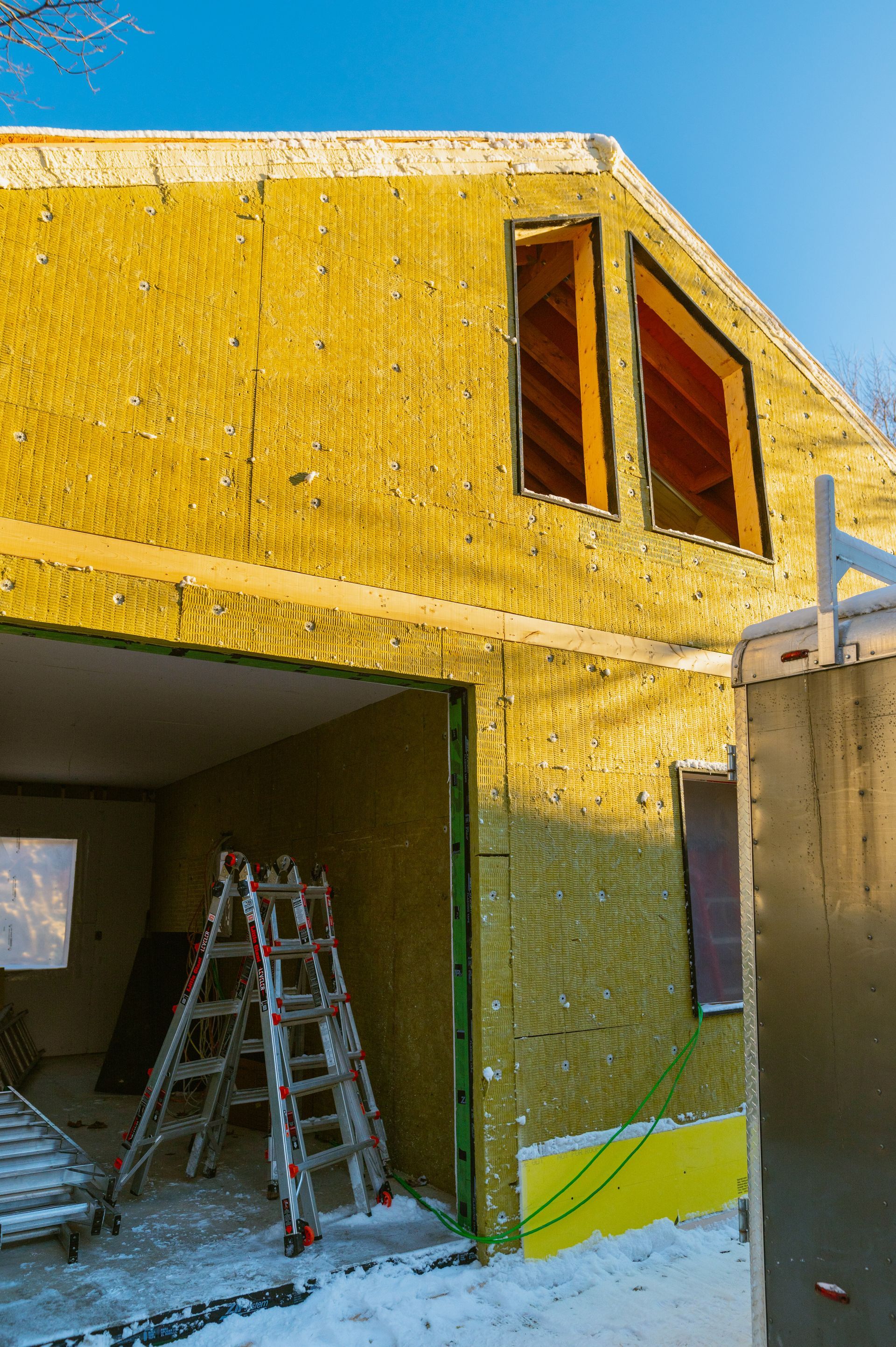 A ladder is sitting in front of a house under construction.
