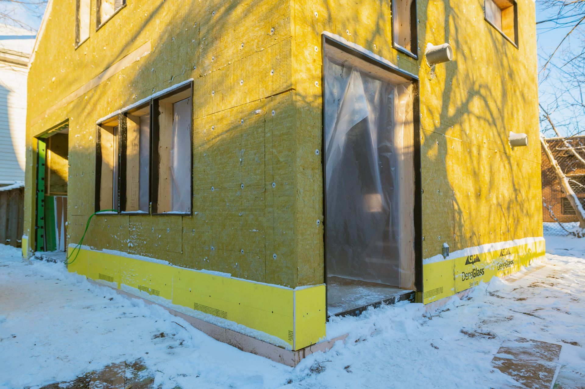 A yellow building with a lot of windows is covered in snow.