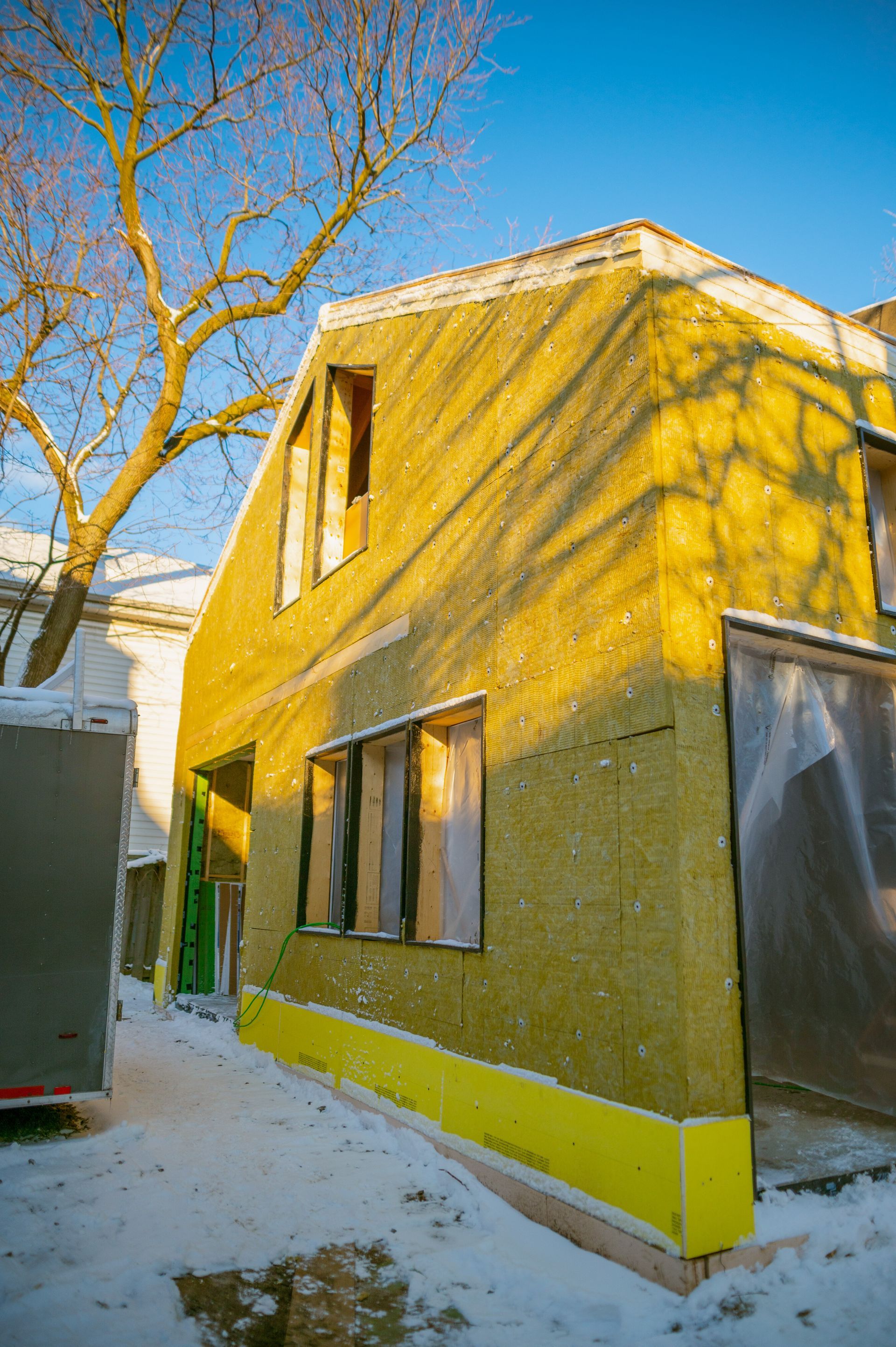 A yellow house is being built in the snow.