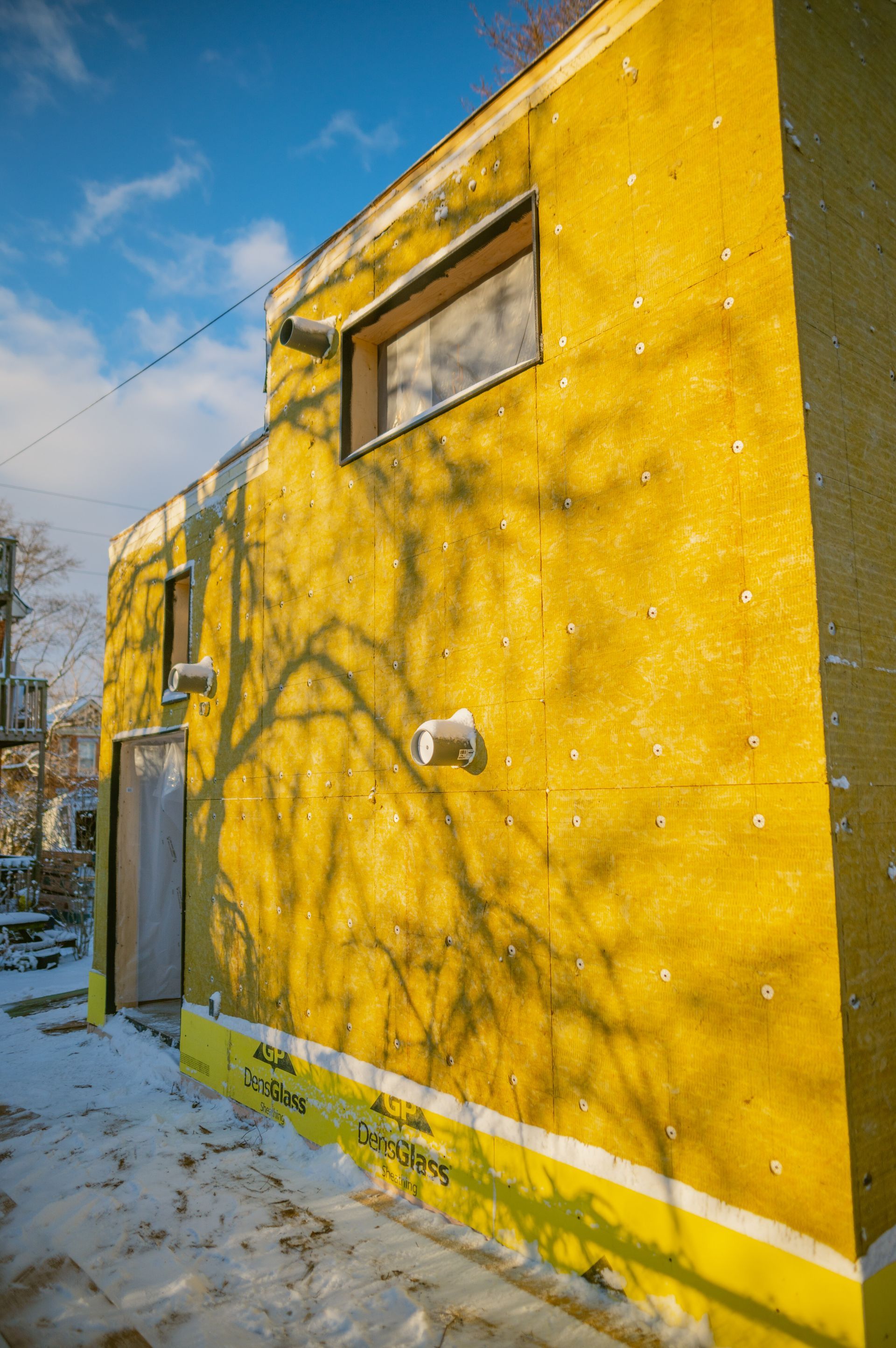 A yellow building with a window is covered in snow.