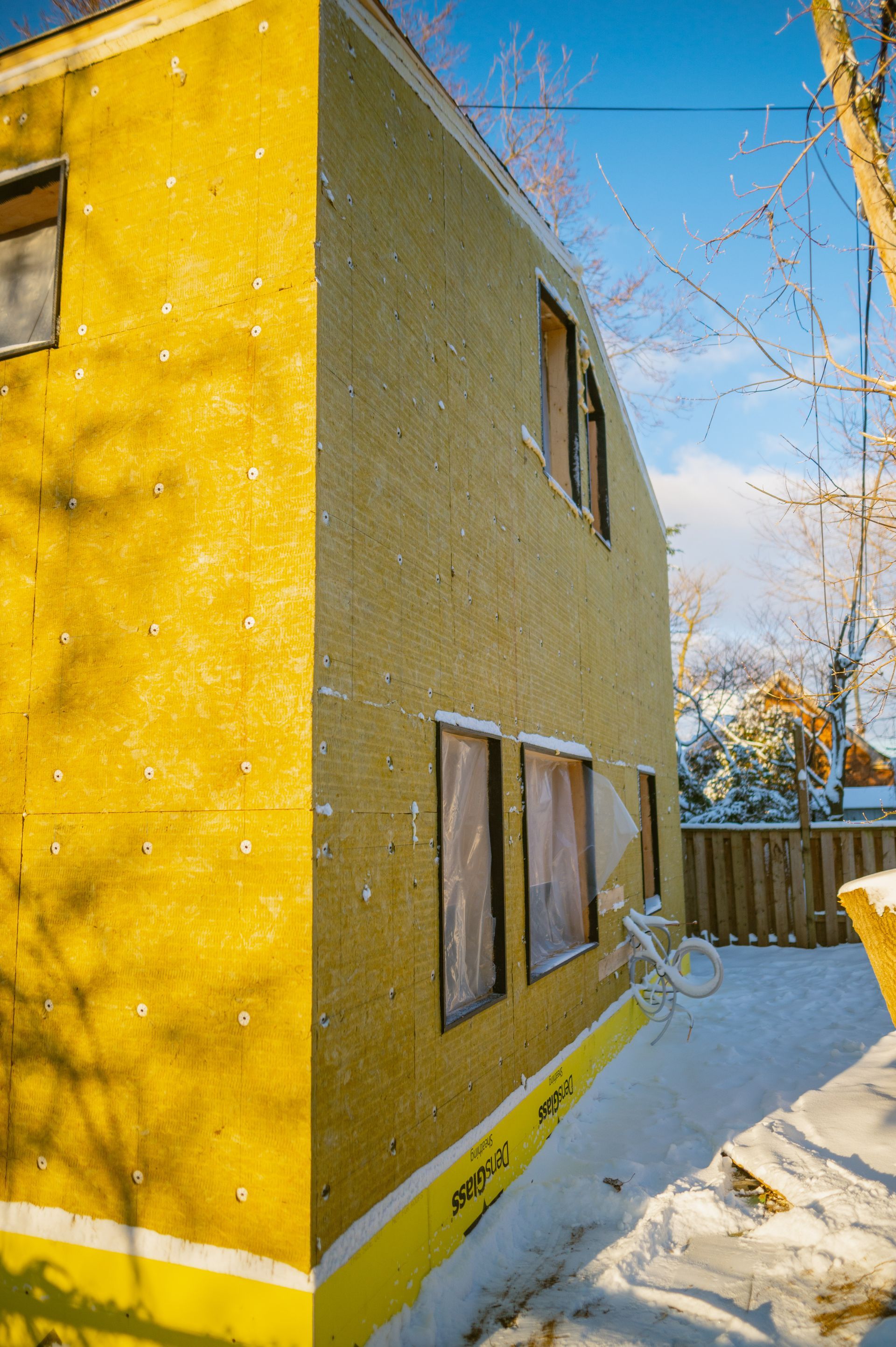A yellow house is being built in the snow.