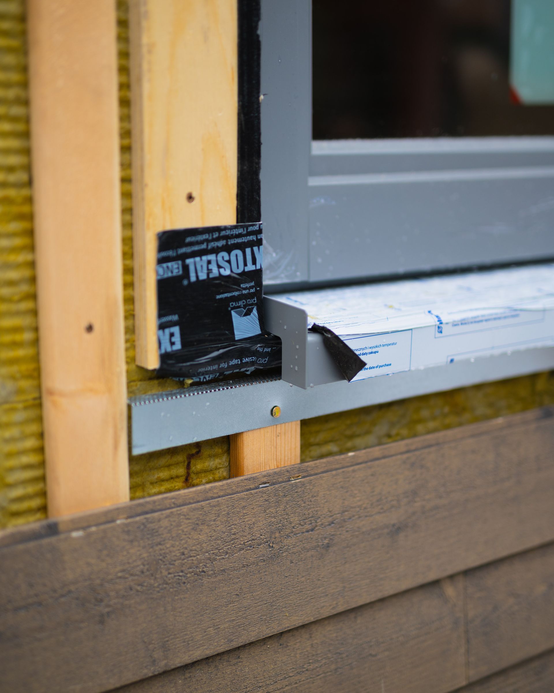 A window is being installed on a wooden wall with a sticker that says ' xtoseal ' on it