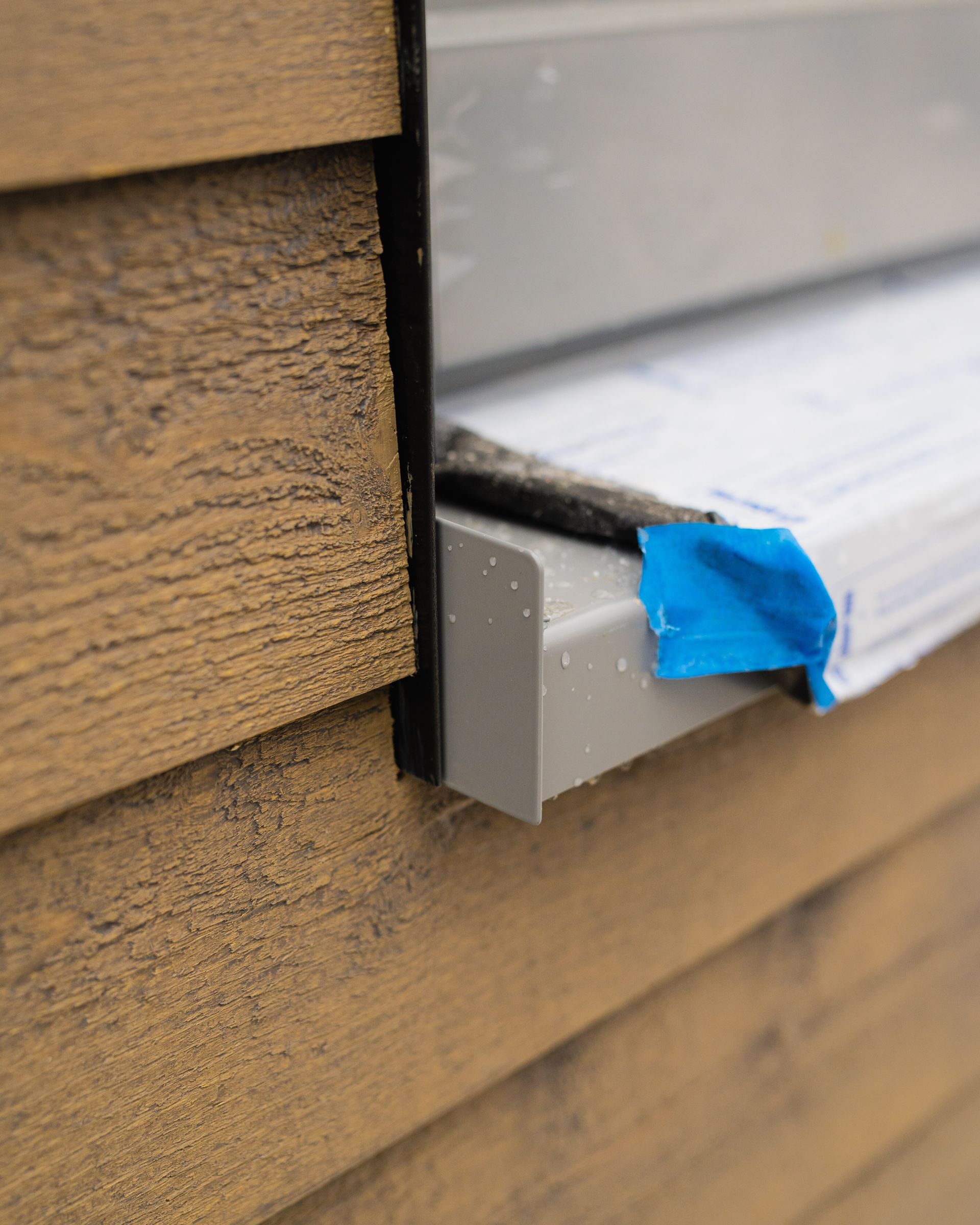 A window sill on a wooden wall with blue tape on it.
