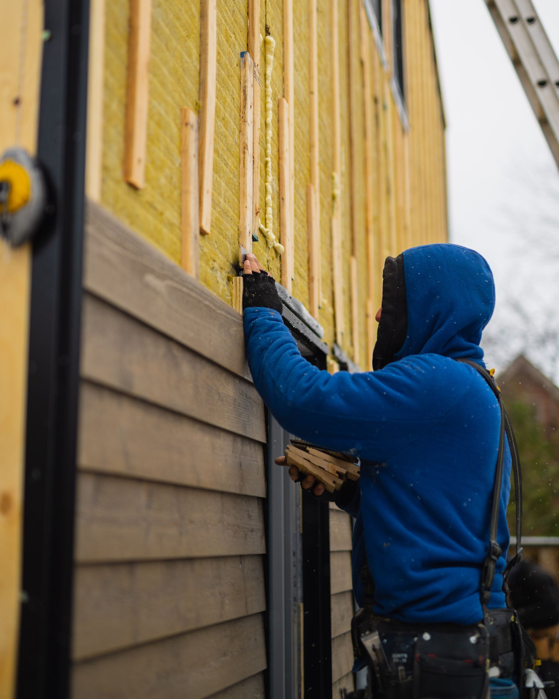 A man in a blue hoodie is working on a building