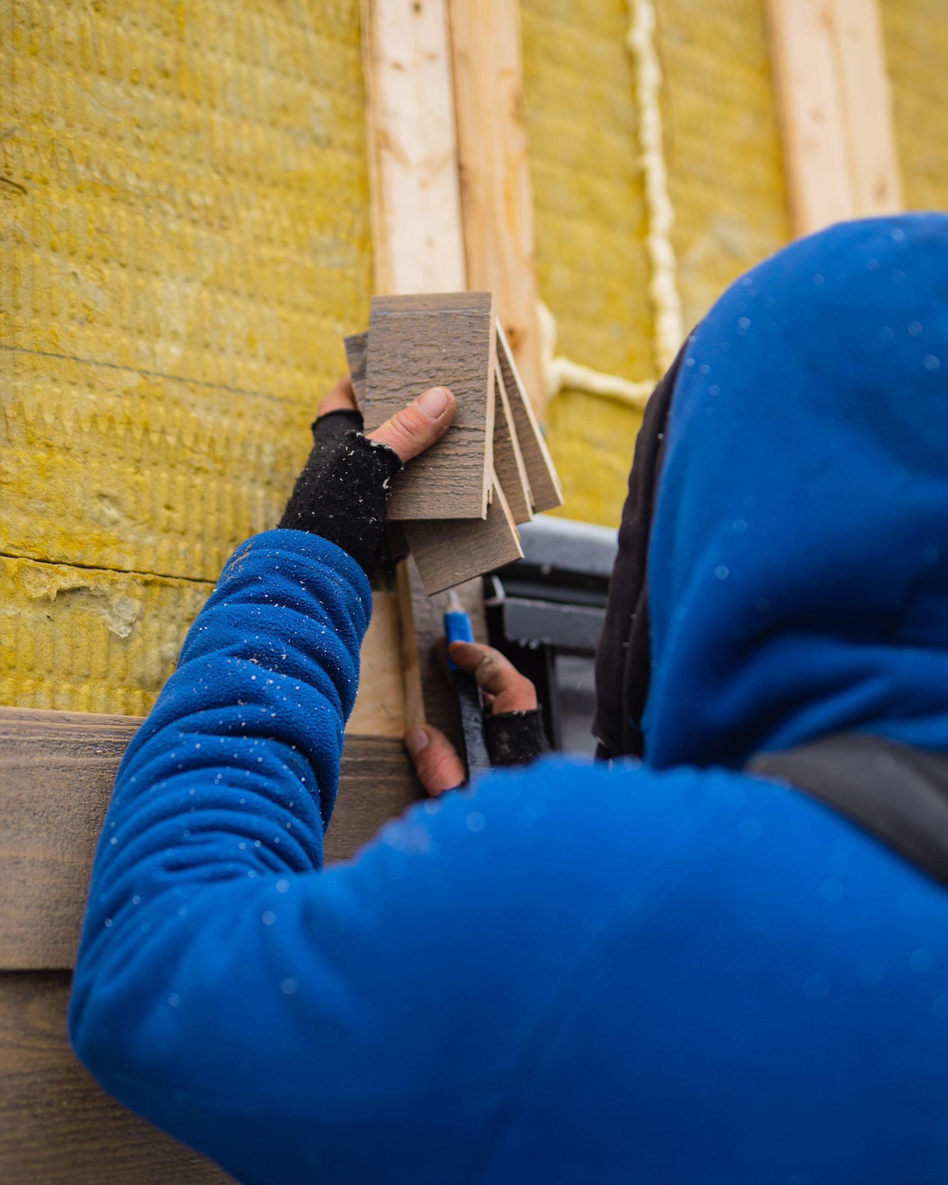 A man in a blue jacket is holding a piece of wood.