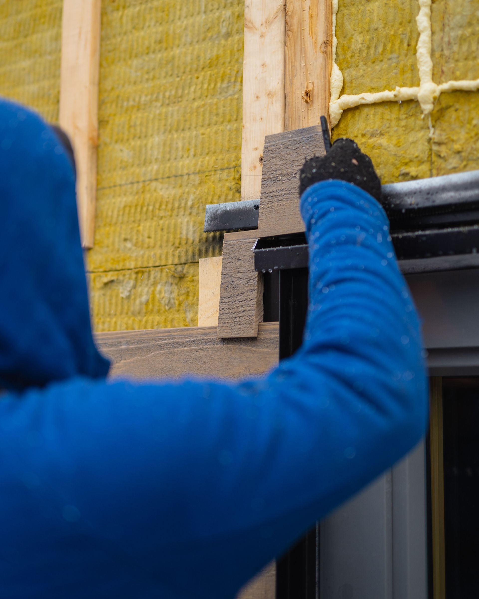 A person in a blue jacket is working on a building.