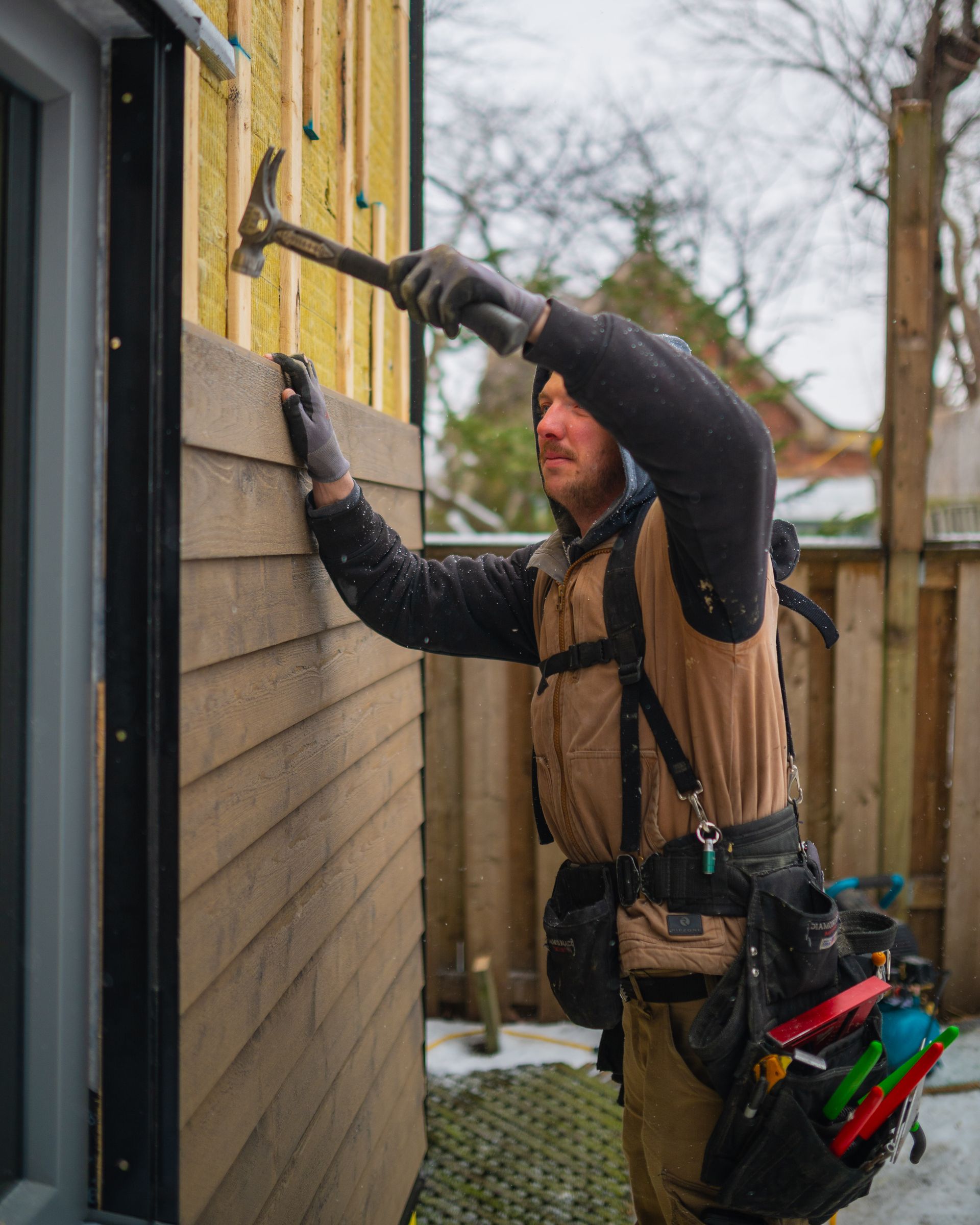 A man is holding a hammer on a wooden wall.