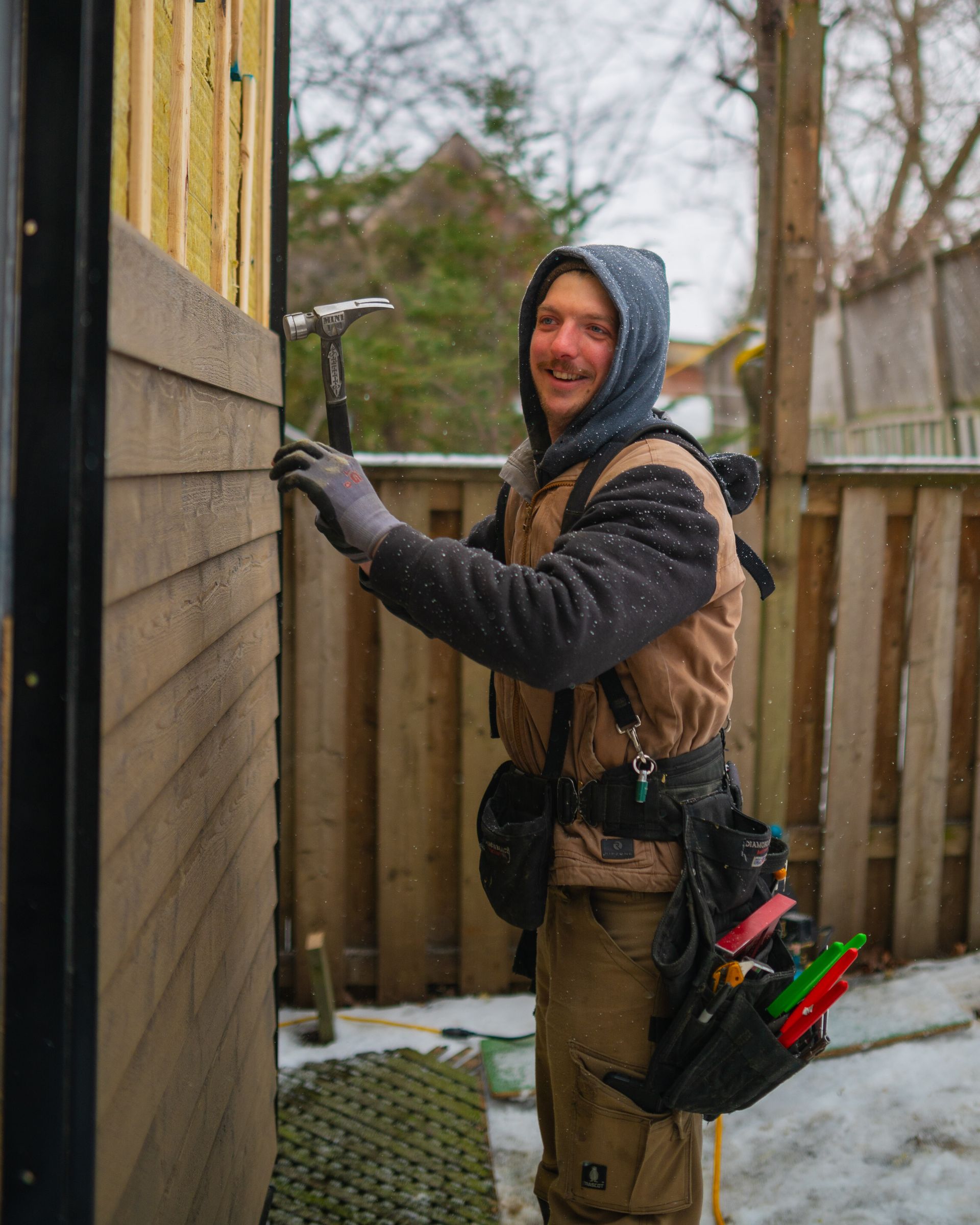 A man is holding a hammer to a wooden wall.