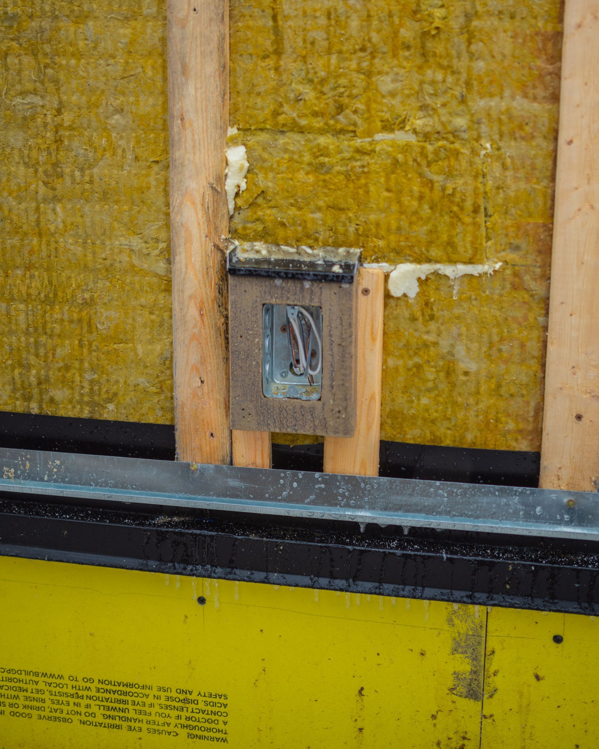 A wooden box with the letter d on it is attached to a yellow wall.