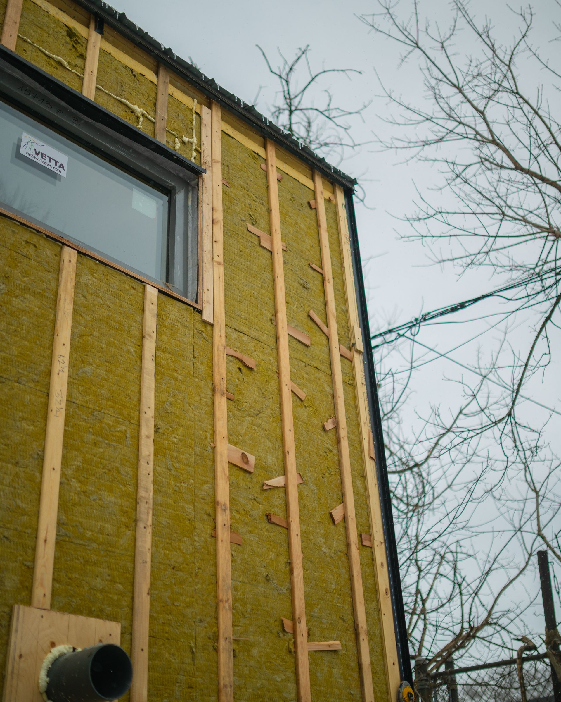 A building is being built with yellow insulation and a window.