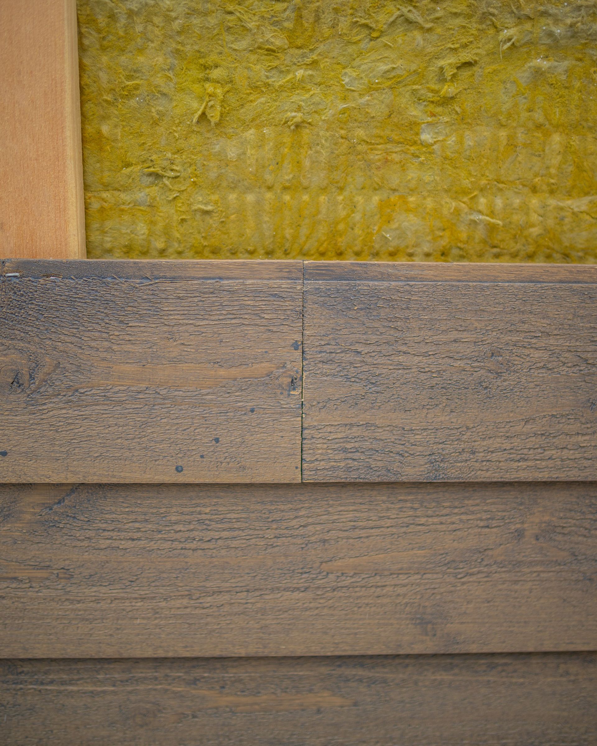 A close up of a wooden wall with insulation on it.