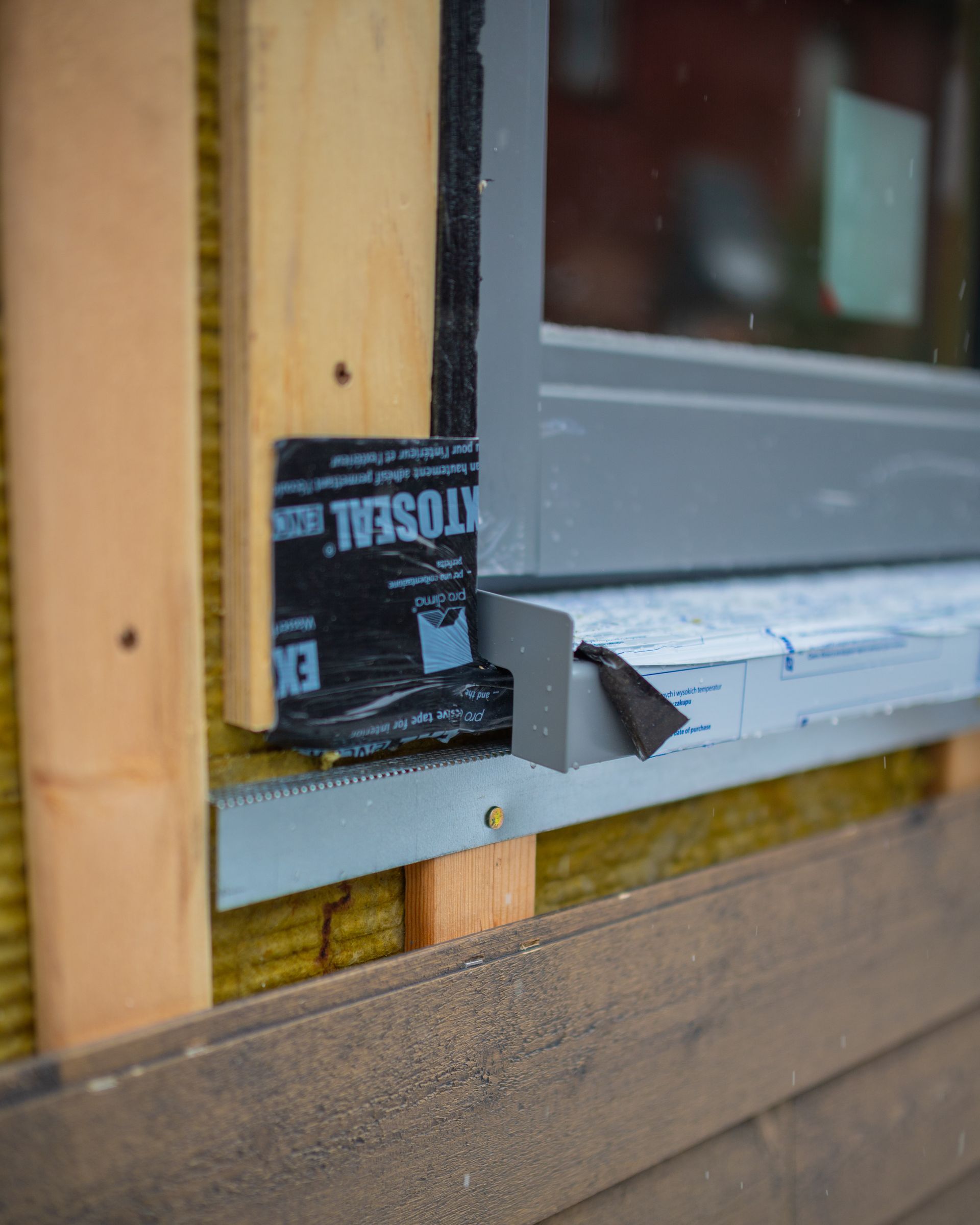 A window is being installed on a wooden wall.