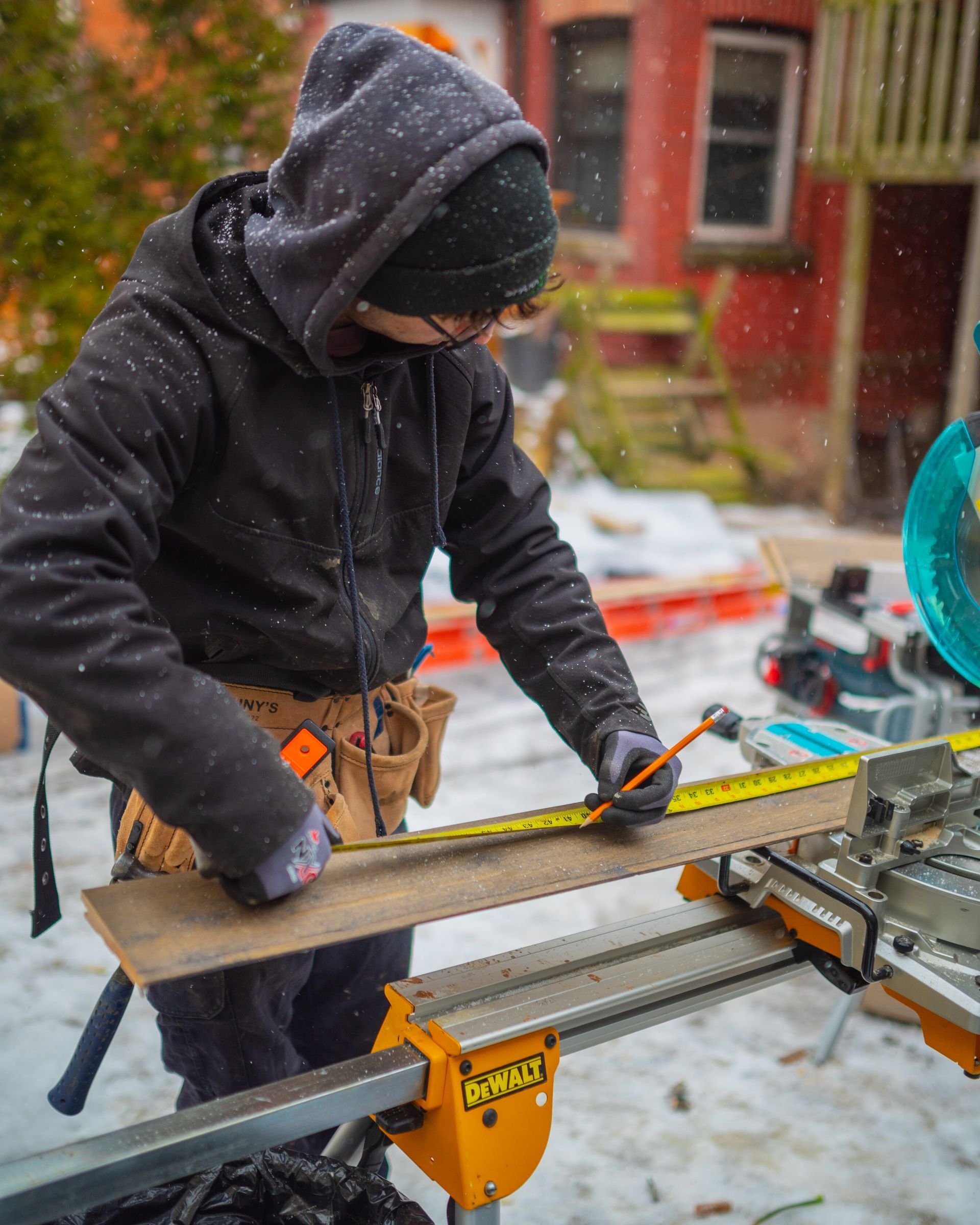 A man is measuring a piece of wood with a tape measure.