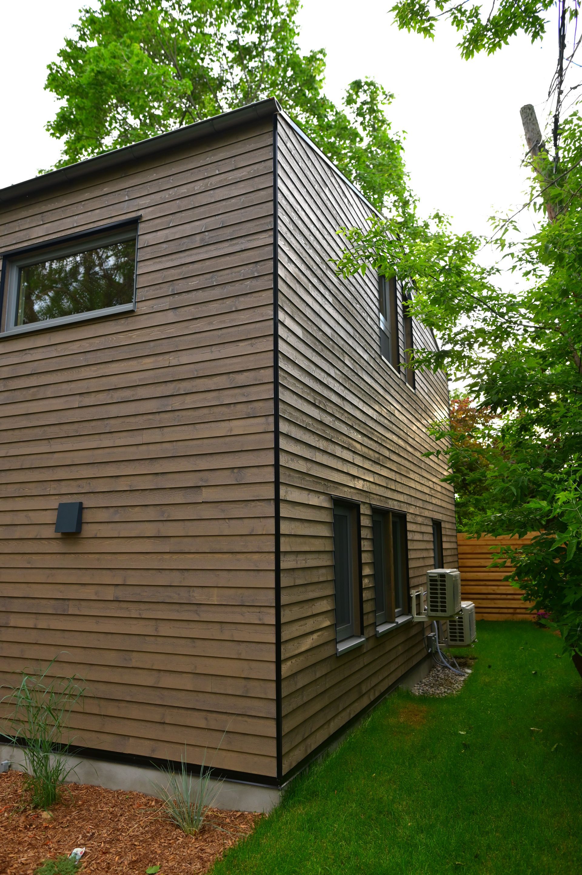 A house with a lot of windows is surrounded by trees