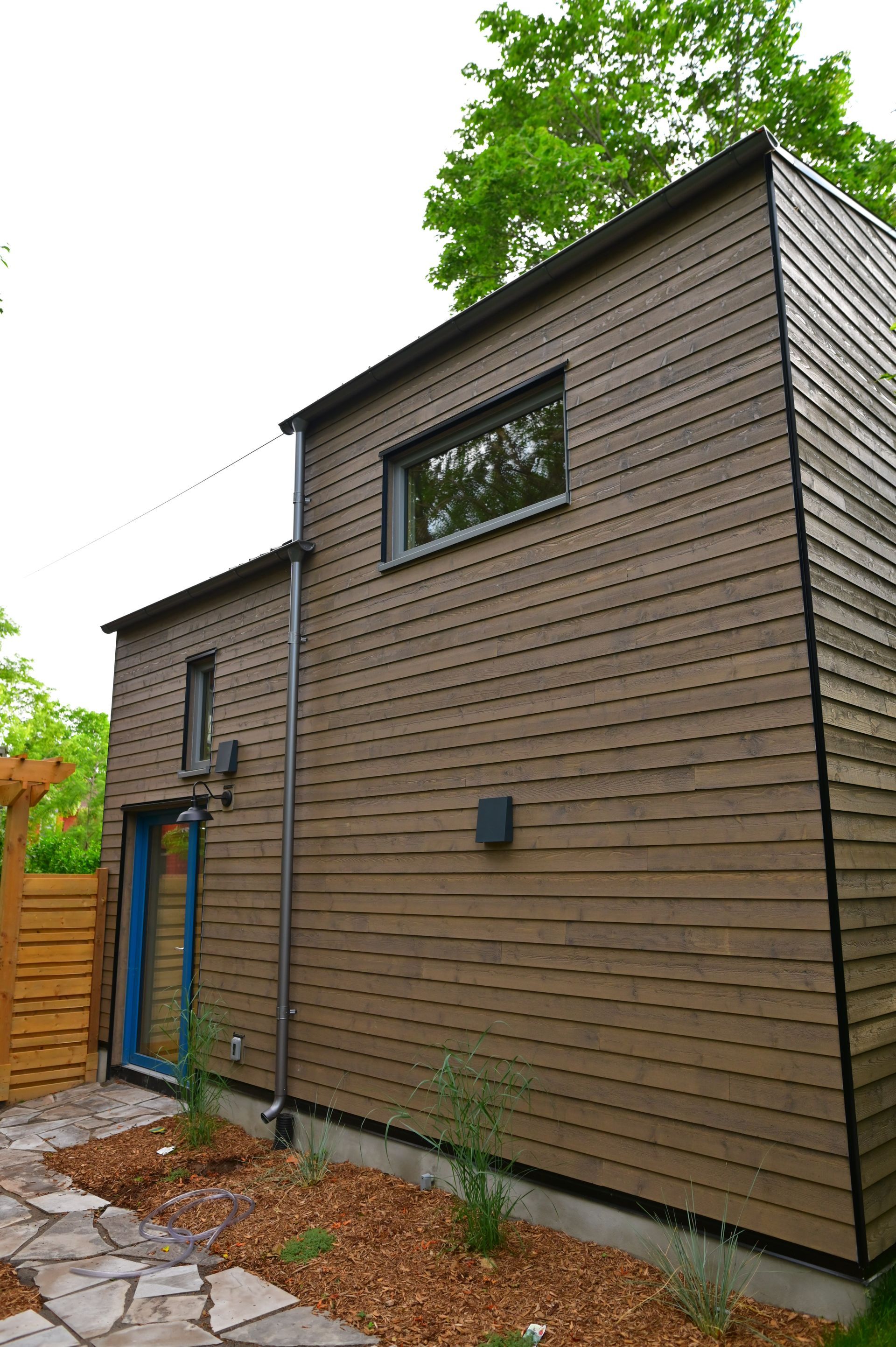 A small house with a wooden siding and a blue door.