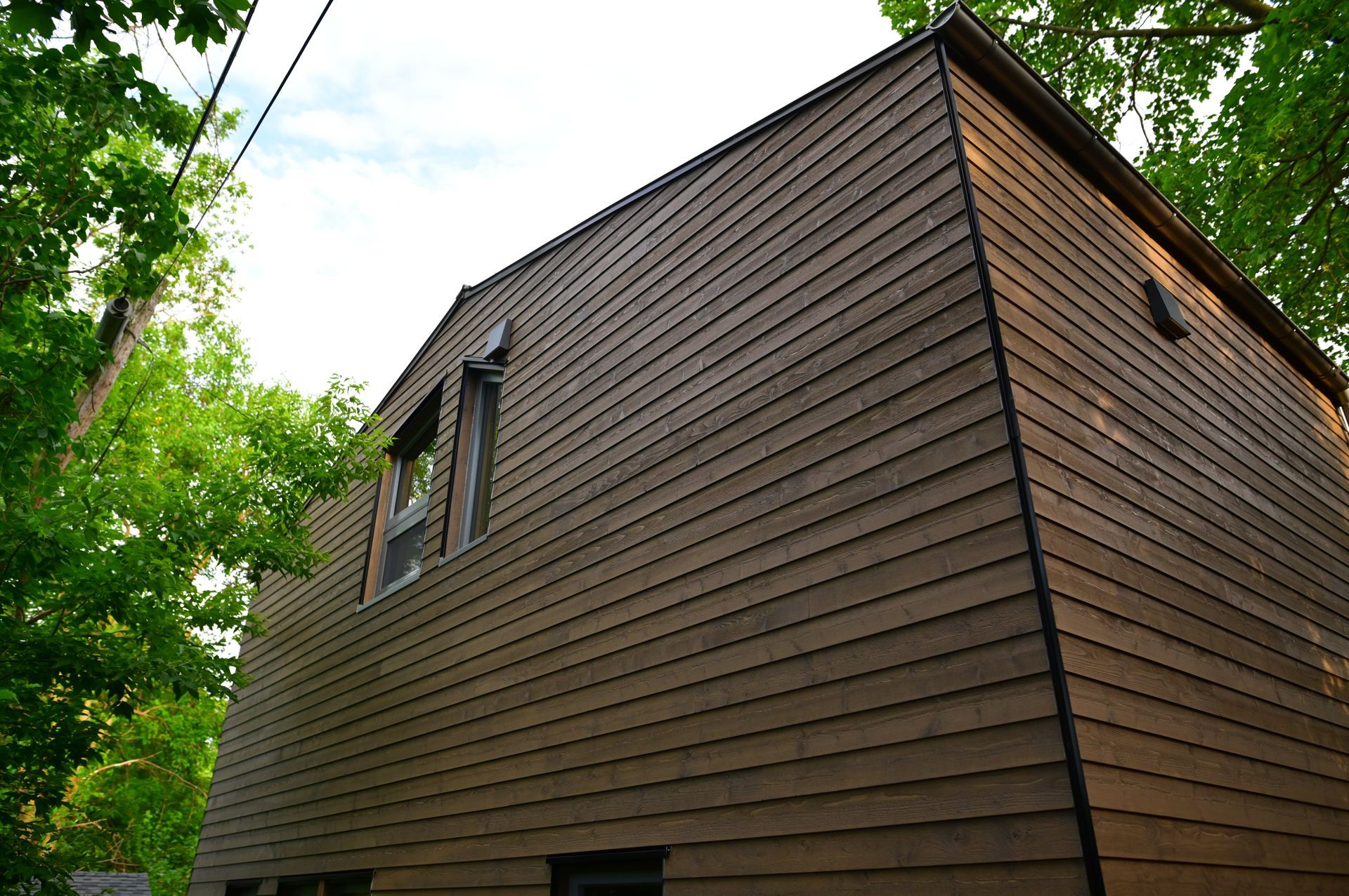 A house with a wooden siding is surrounded by trees