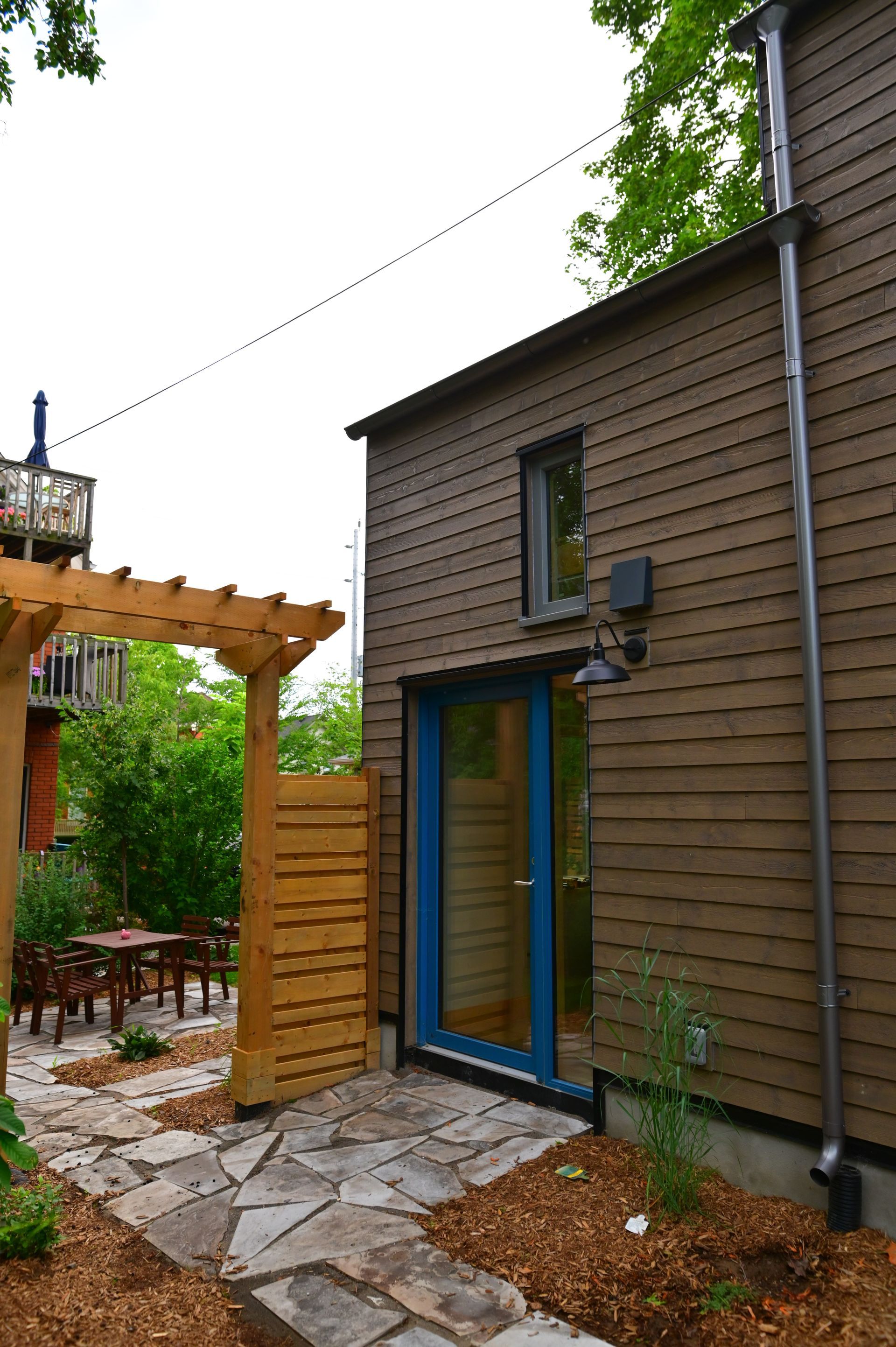 A house with a blue door and a pergola on the side of it.