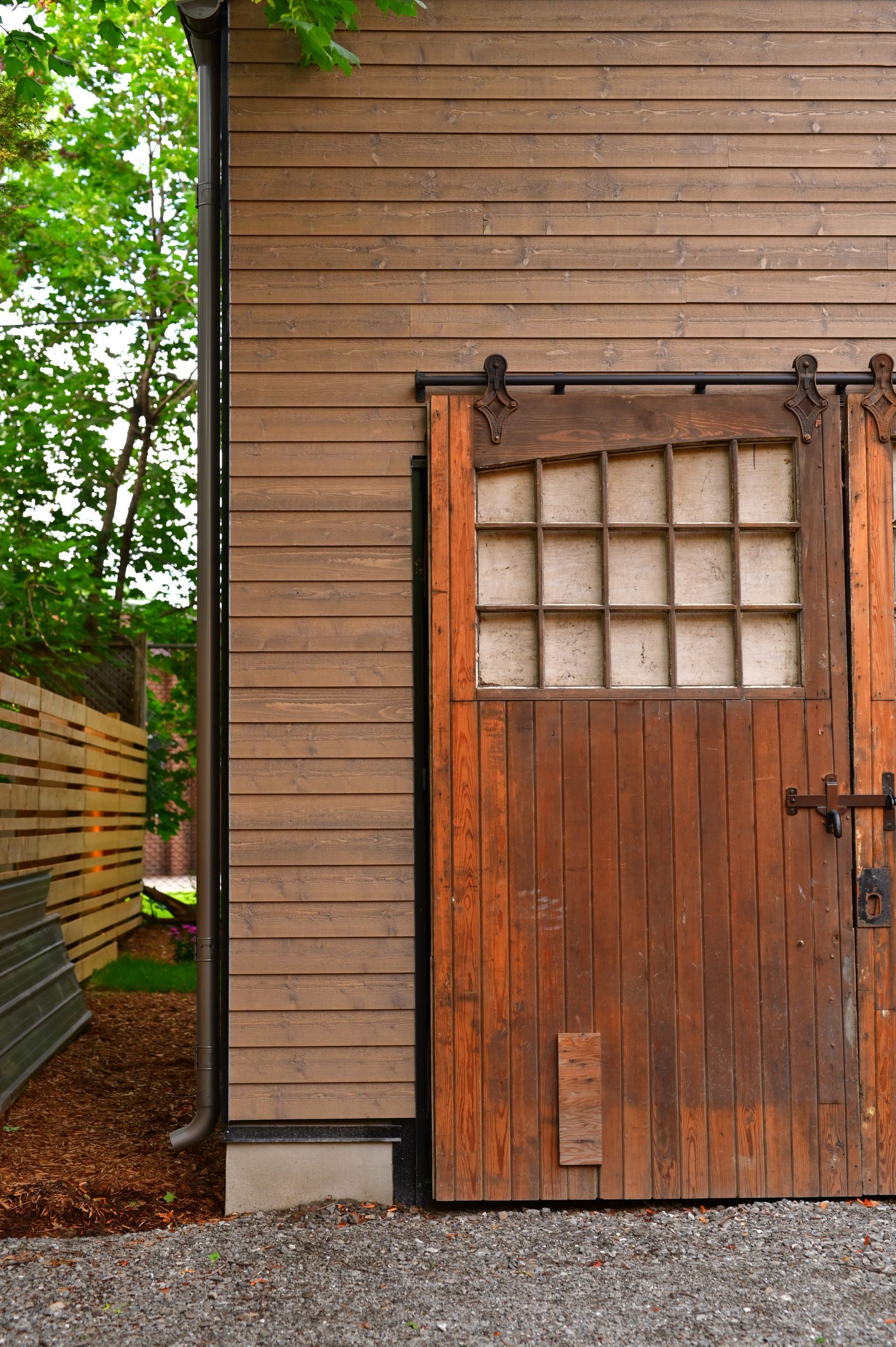 A wooden garage door with a window on the side of a house.
