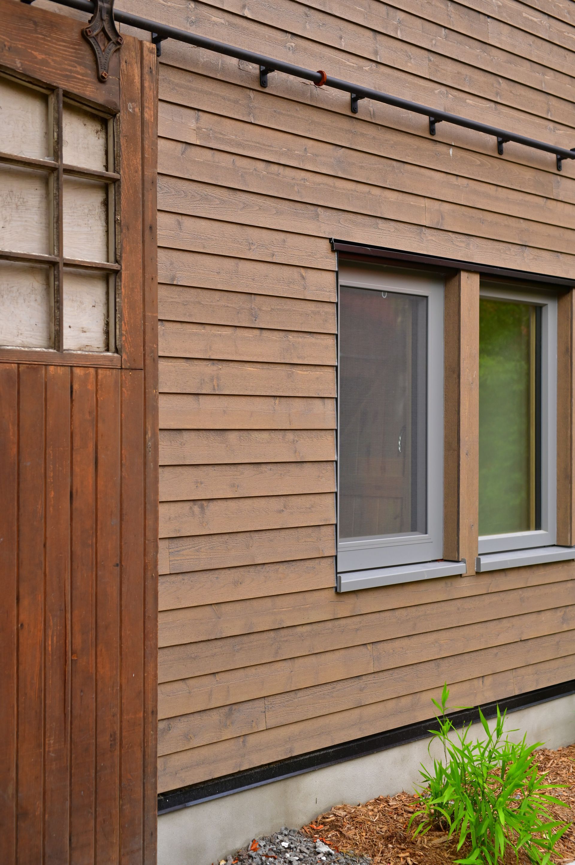A wooden house with a sliding barn door and two windows.