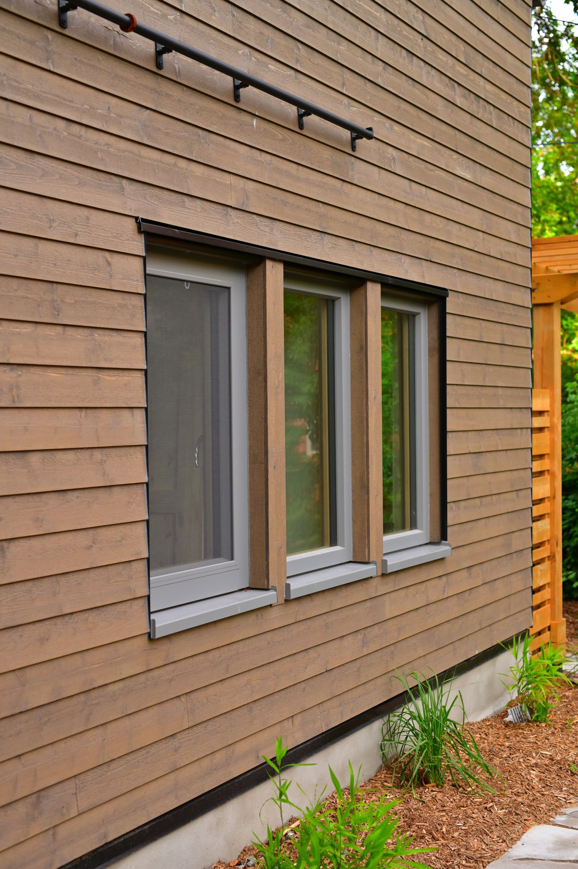 A wooden house with three windows on the side of it