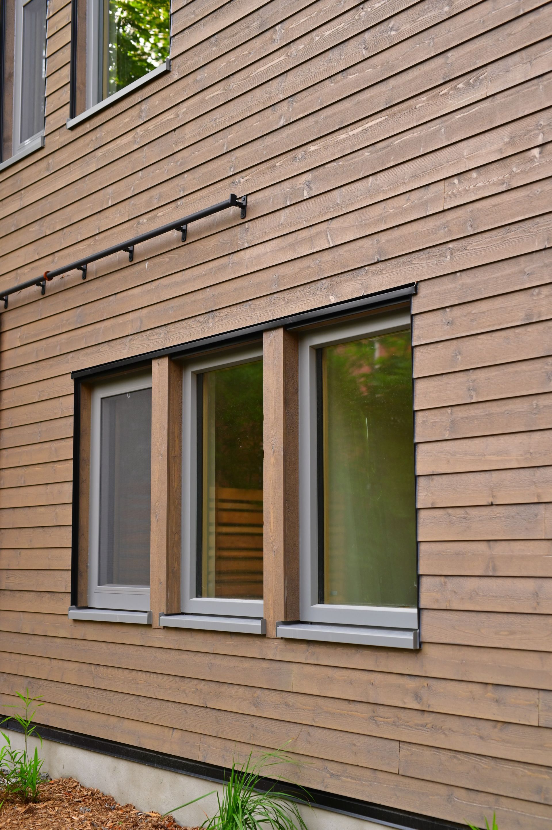 A wooden house with three windows on the side of it.