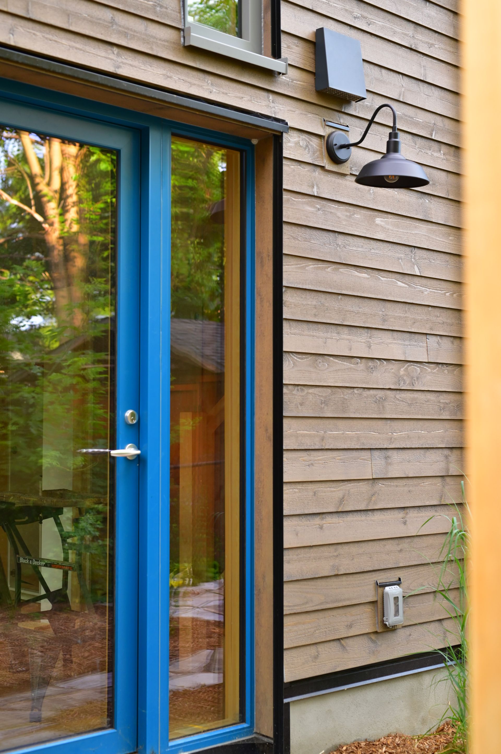 A blue door is on the side of a wooden house.