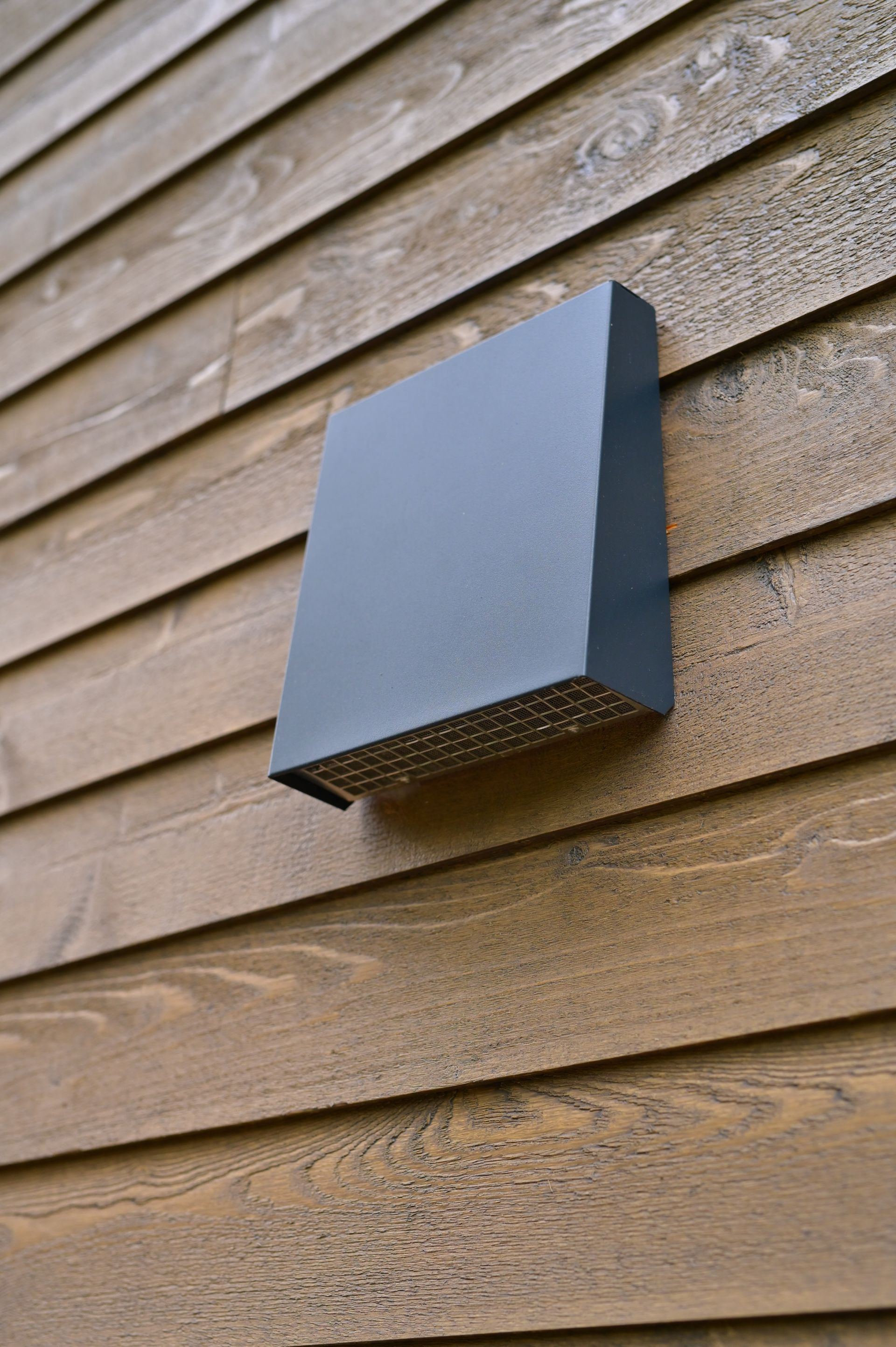 A black box is sitting on the side of a wooden building.