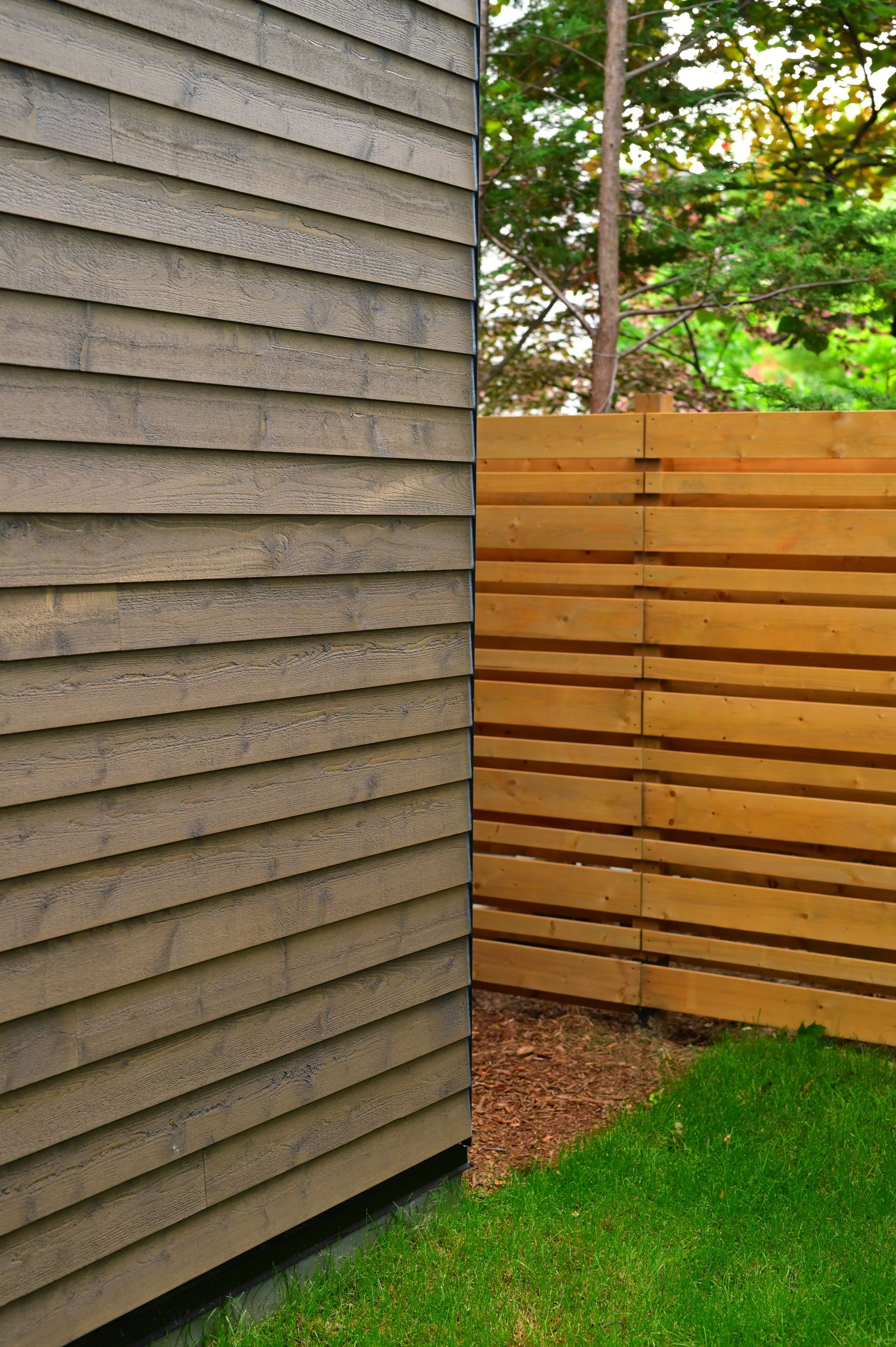 A wooden fence is next to a house with a gray siding