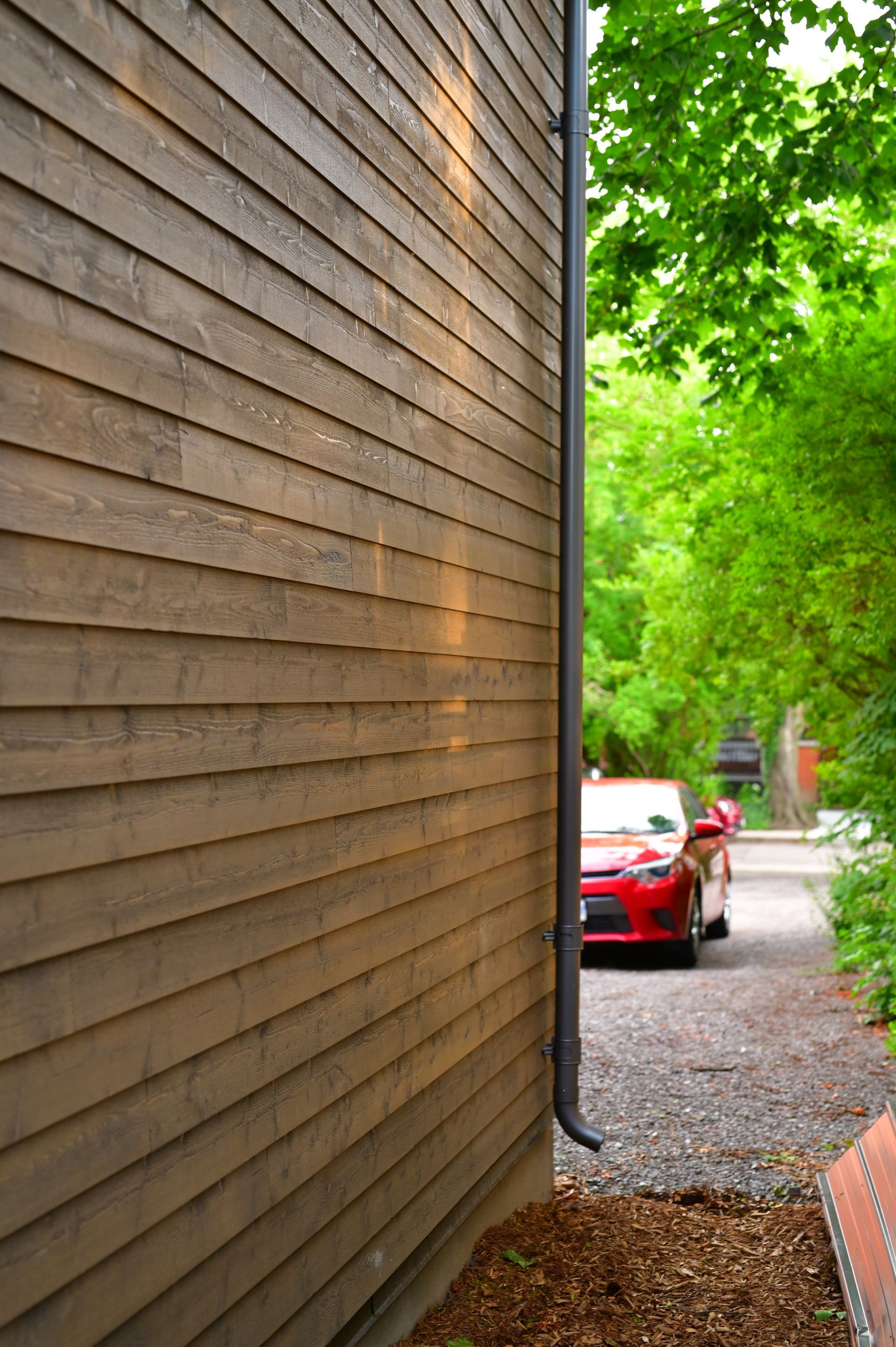 A red car is parked on the side of a house