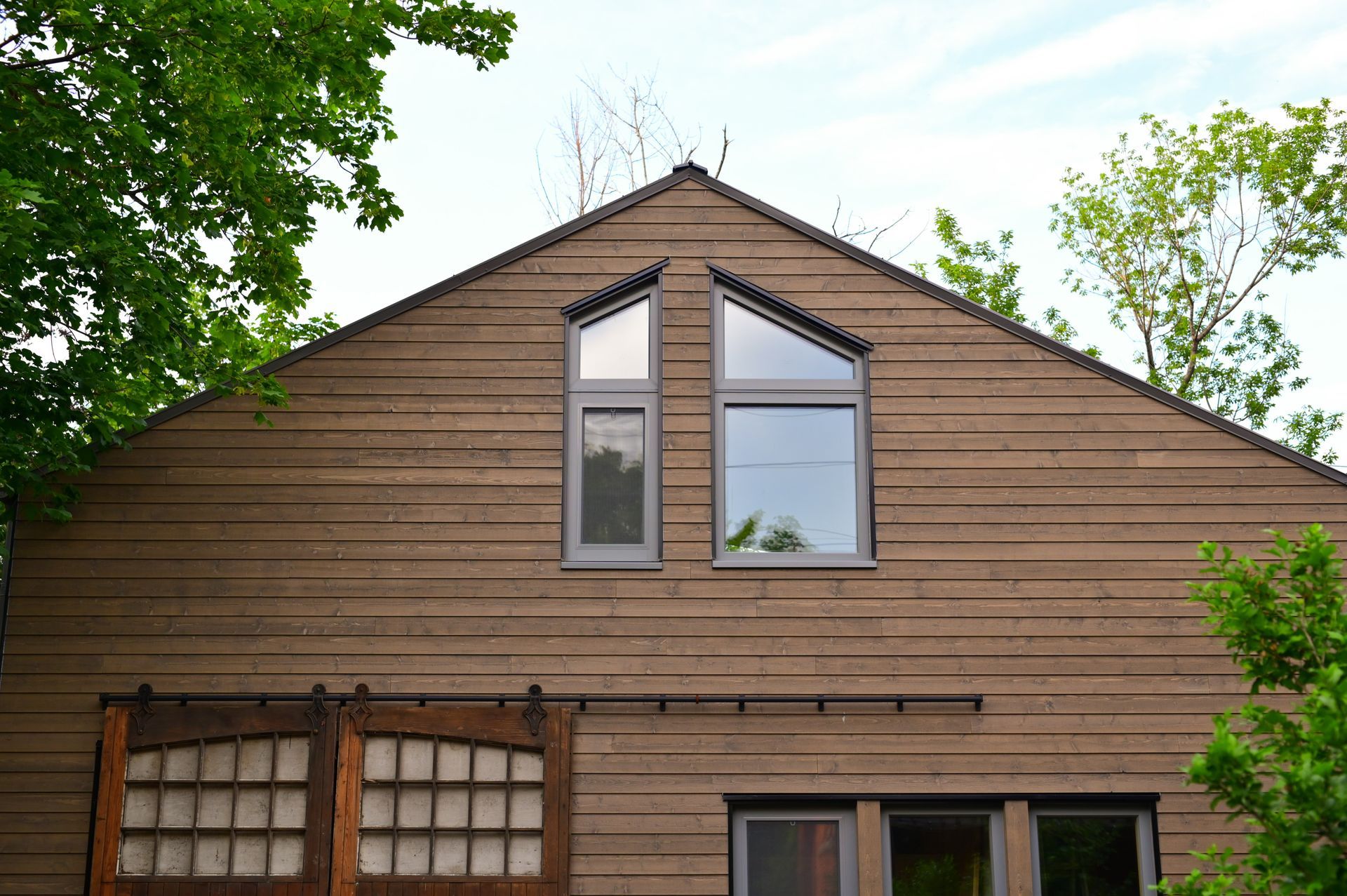 A wooden house with a sliding barn door and a lot of windows.