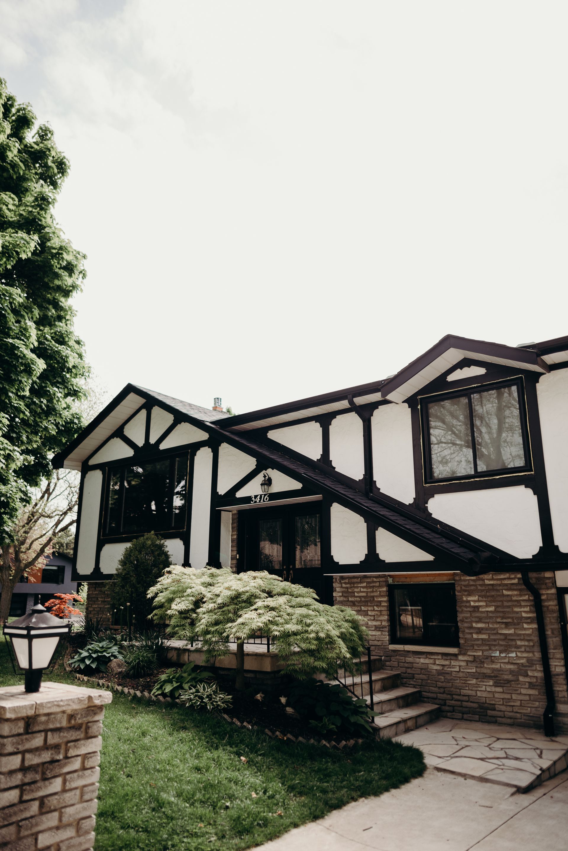 A black and white house with a brick walkway in front of it.