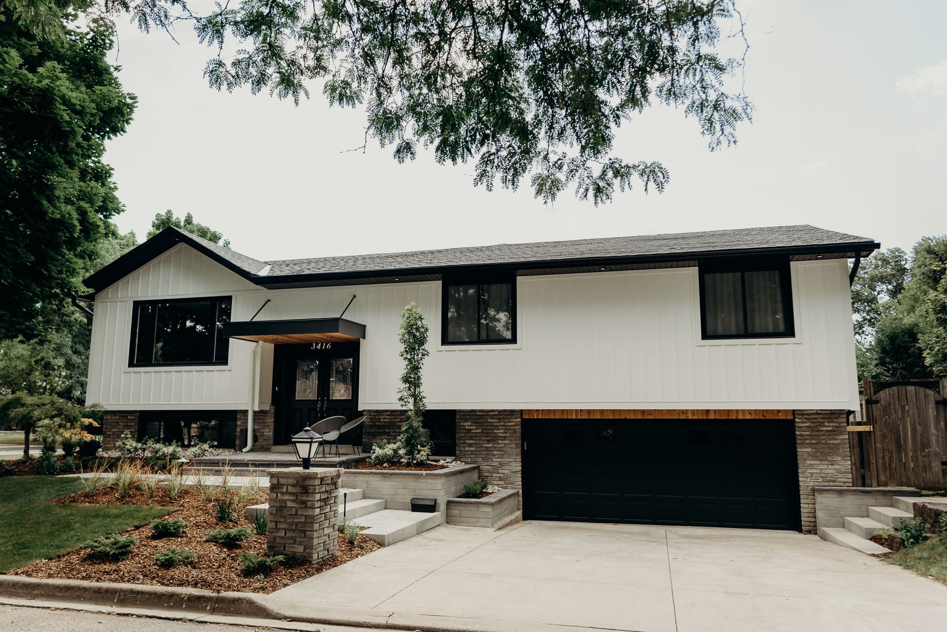 A white house with a black garage door and a black garage door.