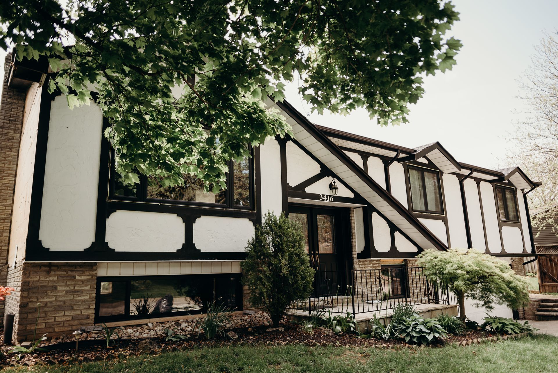A black and white house with a tree in front of it.