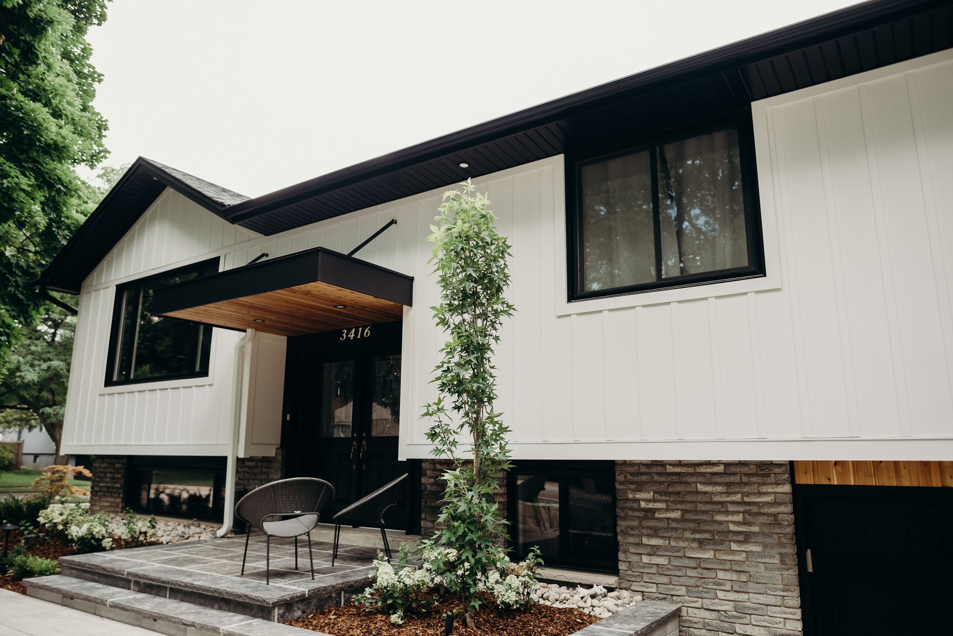 A white house with a black roof and a canopy over the front door.